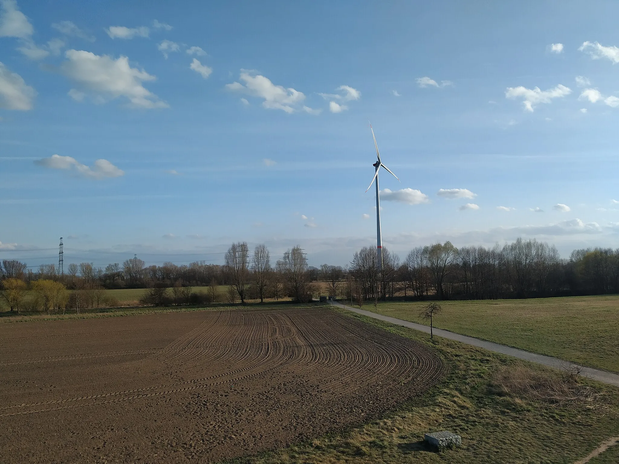 Photo showing: Blick von einem künstlichen Erdhügel im Stadtrandpark Neue Wiesen. Im Hintergrund steht eine Windkraftanlage. Sie wurde 2021 gebaut.