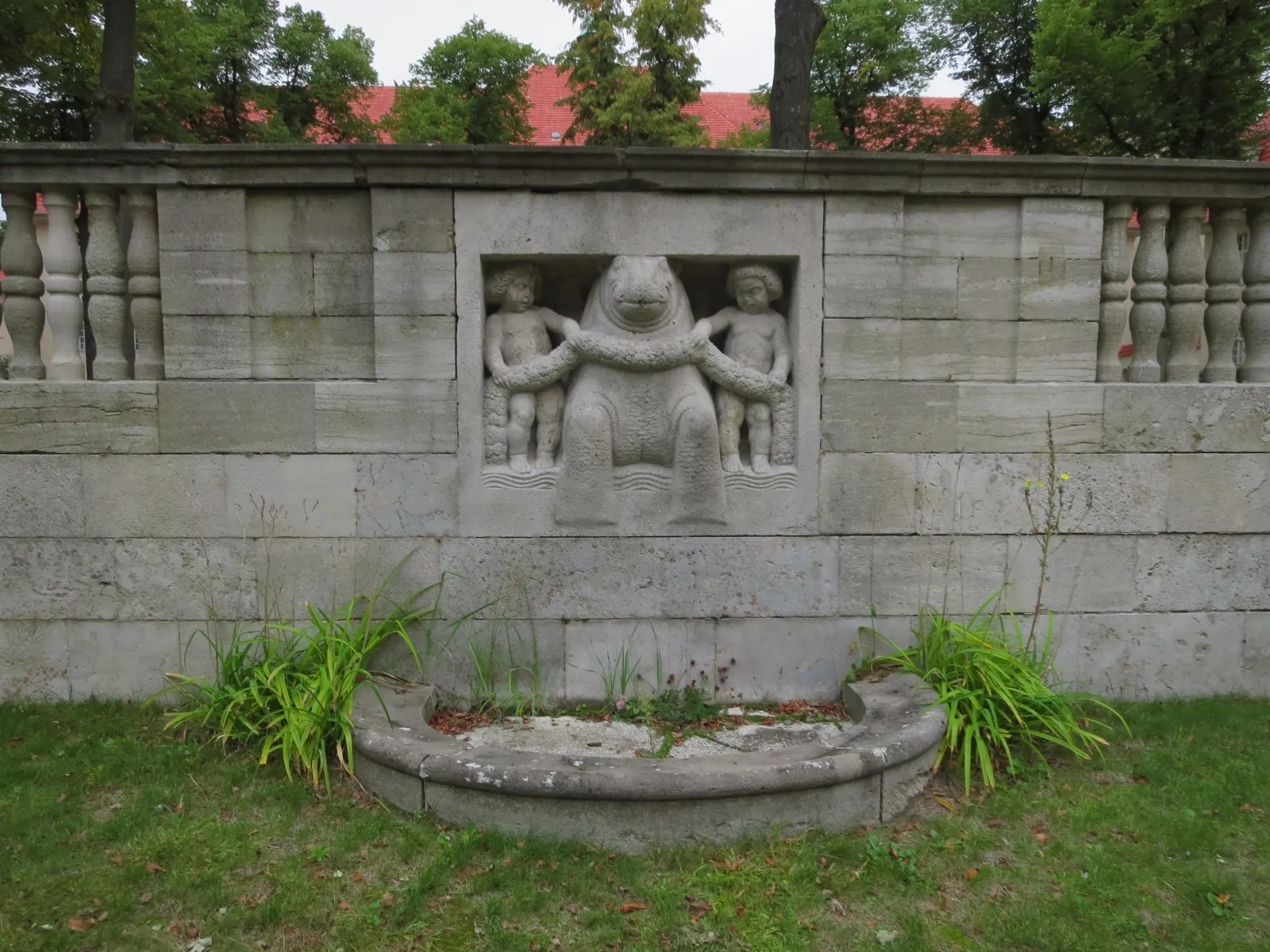 Photo showing: Wandbrunnen von Ignatius Taschner an der östlichen Futtermauer. Zu sehen sind zwei Knabenfiguren, die mit einer Blütengirlande ein flusspferdartiges Tier festhalten. Ursprünglich eine Auftragsarbeit für die Stadt Breslau, Ludwig Hoffmann gab ihr den ironischen Titel "Die Kunst bändigt mit Blumengirlanden den kunstunverständigen Stumpfsinn."