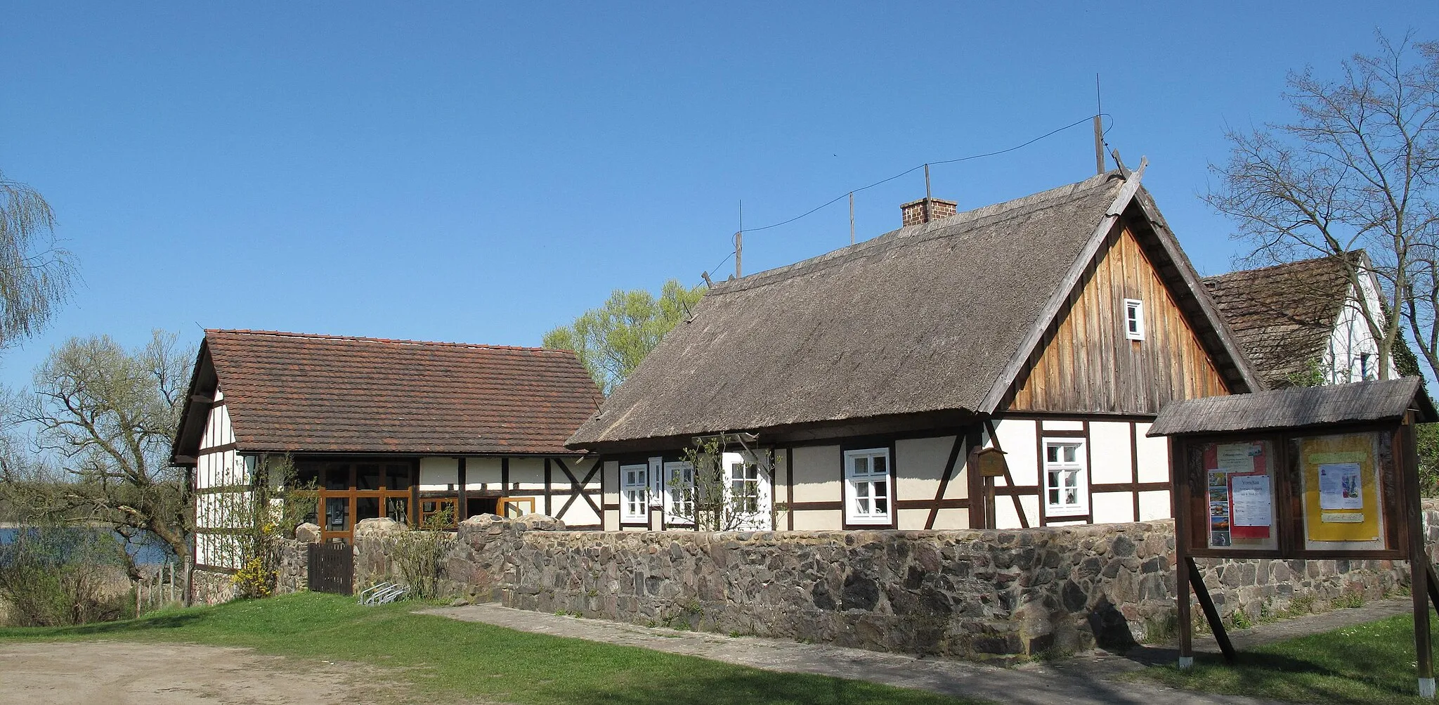 Photo showing: Listed, last and thatched timber framed house in Kähnsdorf. Built around 1700 as private house, between 1825 and 1930 used as school, reconstructed since 1995 and 2001 opened as cultural village hall and local history museum. The Großer Seddiner See is a glacial lake in the nature park Nuthe-Nieplitz in Germany, Brandenburg, district Potsdam-Mittelmark, and covers 2,18 km². The lake is situated in the municipalities Seddiner See and Michendorf.