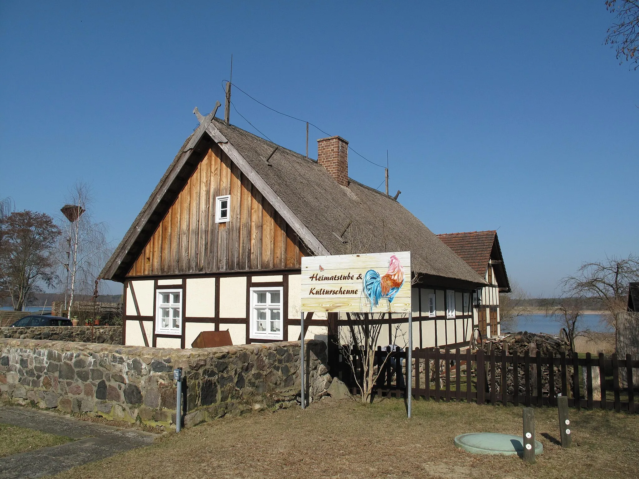 Photo showing: Listed, last and thatched timber framed house in Kähnsdorf. Built around 1700 as private house, between 1825 and 1930 used as school, reconstructed since 1995 and 2001 opened as cultural village hall and local history museum. The Großer Seddiner See is a glacial lake in the nature park Nuthe-Nieplitz in Germany, Brandenburg, district Potsdam-Mittelmark, and covers 2,18 km². The lake is situated in the municipalities Seddiner See and Michendorf.
