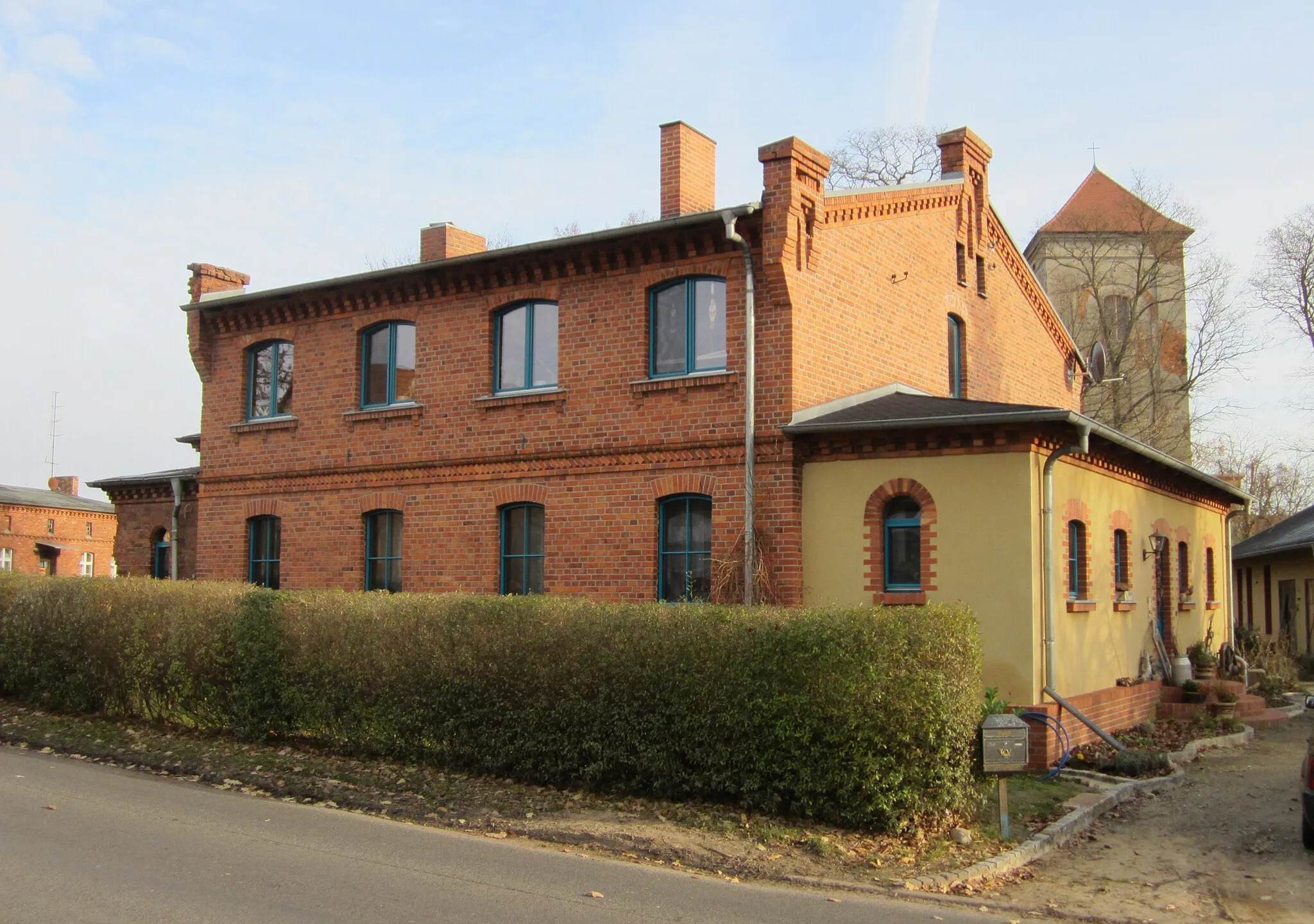 Photo showing: Listed manor workers house with belonging outbuilding at square Platz der Einheit 12 with the tower of the village church in background in Lossow, Frankfurt (Oder), Brandenburg, Germany