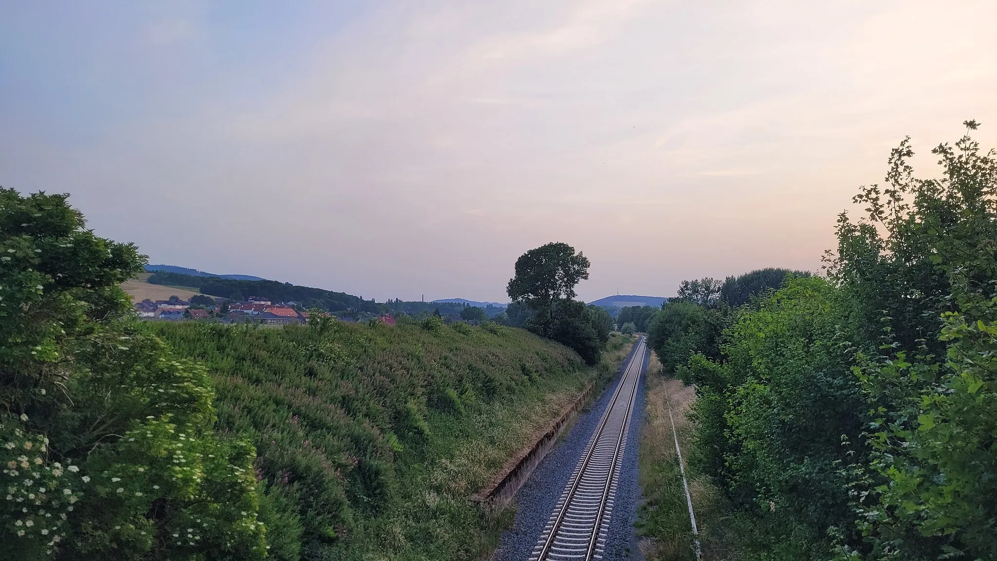 Photo showing: Bahnstrecke Bad Harzburg–Oker bei Kilometer 34,6 im Juni 2022. Im Hintergrund, von links nach rechts: Langenberg, Harlingerode, Sudmerberg mit Sender Goslar.