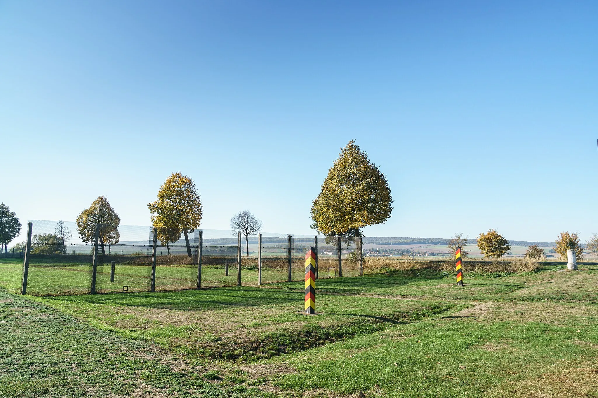 Photo showing: Blick von Niedersachsen zum rekonstruierten Grenzsignalzaun (Grenzdenkmal Hessendamm) in Winnigstedt OT Mattierzoll. Am rechten Bildrand ein Preußischer Meilenstein