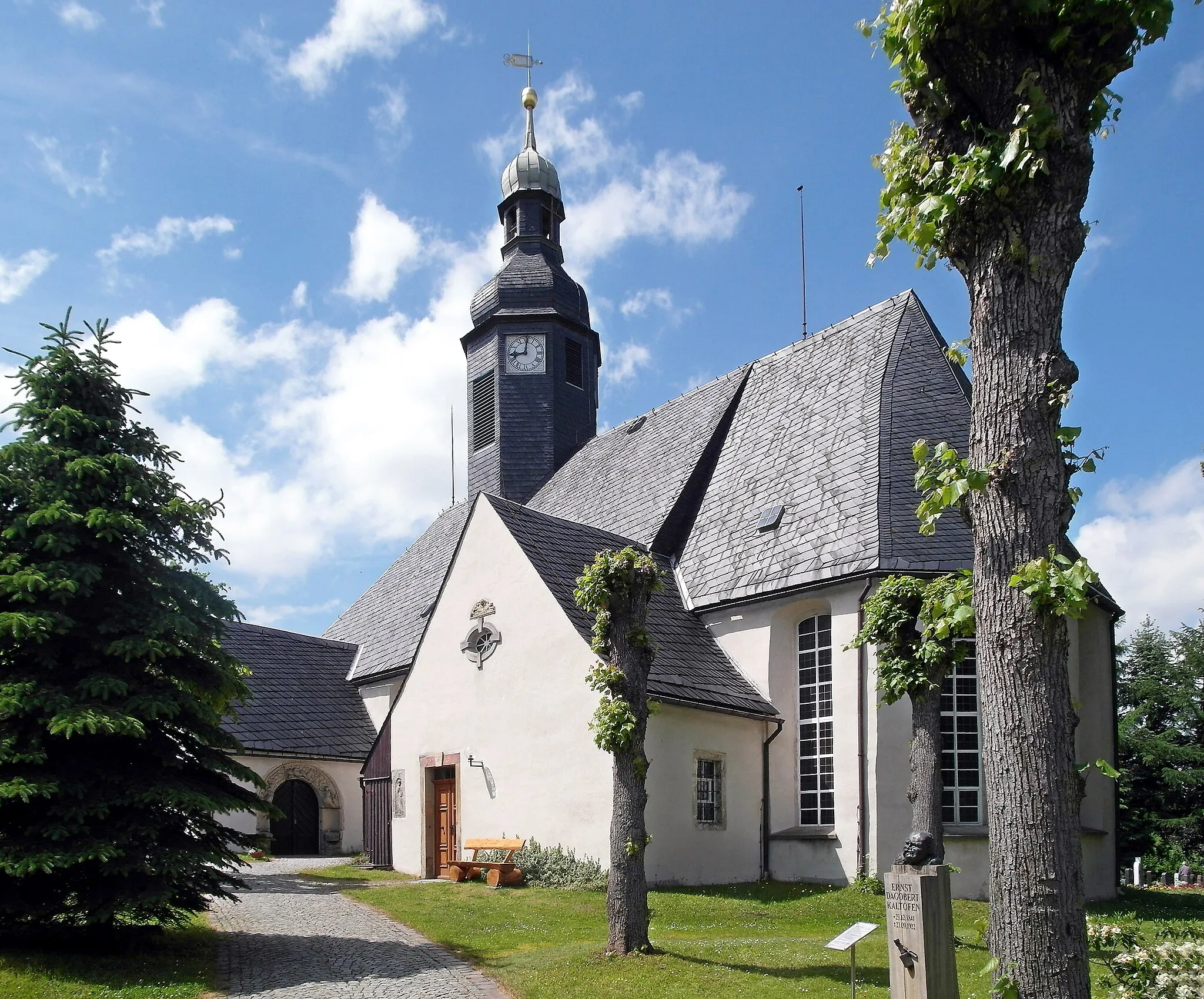 Photo showing: 10.06.2015  09618  Langenau (Brand-Erbisdorf), Kirchberg: Kirche Langenau (GMP: 50.837329,13.295281) mit dem Renaissance-Sitznischenportal vom nach 1945 gesprengten Herrenhauses Niederlangenau. Das genaue Erbauungsjahr der Langenauer Kirche ist nicht mehr feststellbar. Eine Pfarrkirche soll es bereits im Jahr 1162 gegeben haben. Urkundlich erwähnt wurde Langenau erstmalig 1185. Die heutige Form einer einschiffigen dörflichen Saalkirche stammt vermutlich aus dem 16. Jahrhundert.                                                                                                                                                                                                                       [SAM0924.JPG]20150610545DR.JPG[c)Blobelt