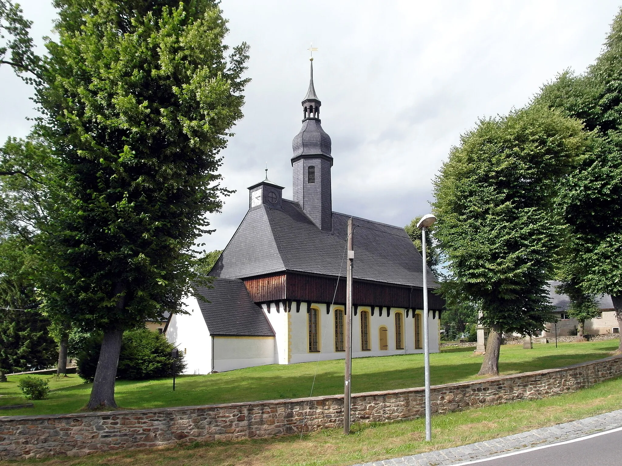 Photo showing: 18.07.2016    09618  Mittelsaida (Großhartmannsdorf): Wehrkirche (GMP: 50.763437,13.304965). Das vermutlich um 1450, nach den Hussitenkriegen, errichtete Gebäude diente neben dem Gottesdienst auch dem Schutz der Bevölkerung und der Paßstraßen nach Böhmen. Das Wehrgeschoß wurde 1475 gebaut. Die Kirche wurde 1581 (Choranbau), 1701 (Erneuerung des Dachreiters) und 1728 (Erweiterung nach Norden) umgebaut und erweitert. Bis 2003 wurden umfangreiche Sanierungsmaßnahmen durchgeführt.                            [SAM7143.JPG] 20160718800DR.JPG(c)Blobelt