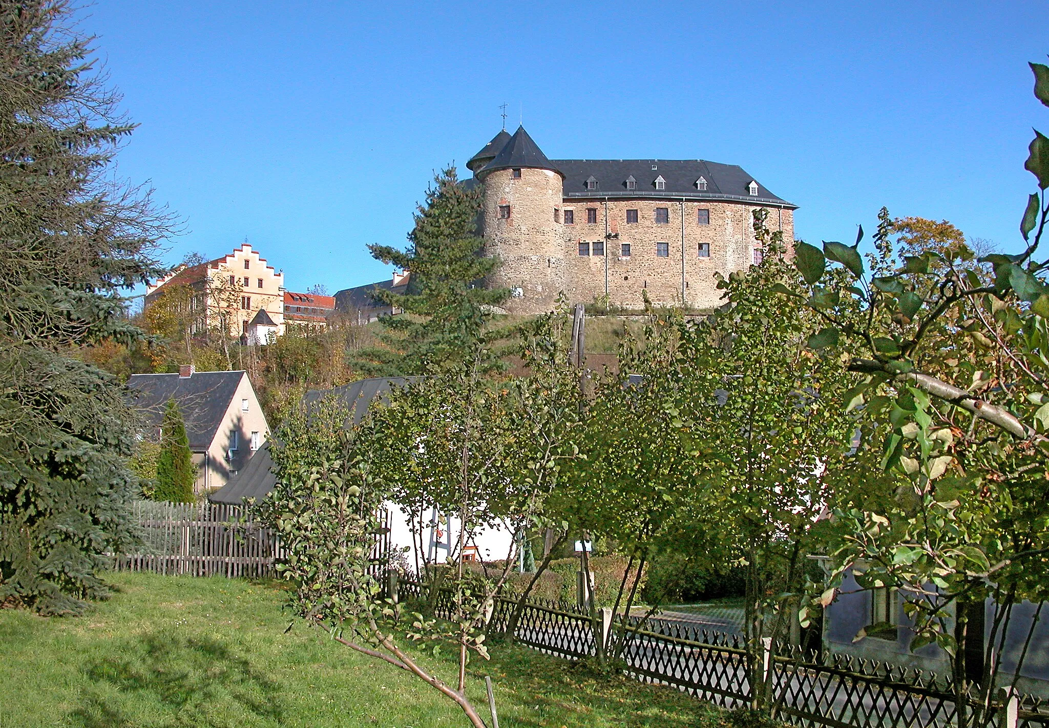 Photo showing: 15.10.2007  08606  Voigtsberg (Oelsnitz) Schloßstraße 32: Burg/Schloß Voigtsberg (GMP: 50.422280,12.183285). Die Burg (rechts) wurde vermutlich in der Zeit von 1232 bis 1249 durch Eberhard von Voigtsberg errichtet. 1865 legte man in das Schloß (links) eine "Gefängnisanstalt für Weiber", die 1924 wieder aufgelöst wurde. Der älteste erhaltene Teil ist der Bergfried mit 22 m Höhe und einer Mauerstärke von 3,30 m, in dessen unterem Teil sich einst das Burgverlies befand. In einem Teil des Schlosses befindet sich das 1937 eingerichtete Teppich- und Heimatmuseum der Stadt Oelsnitz. In der DDR war auf der Burg ein Jugendwerkhof untergebracht, danach eine Kaserne der Nationalen Volksarmee (NVA), bis 1967 die Stadt Oelsnitz die Burg in ihren Besitz nahm. Sicht von Süden.                                            [DSCN30674.TIF]20071015610DR.JPG(c)Blobelt