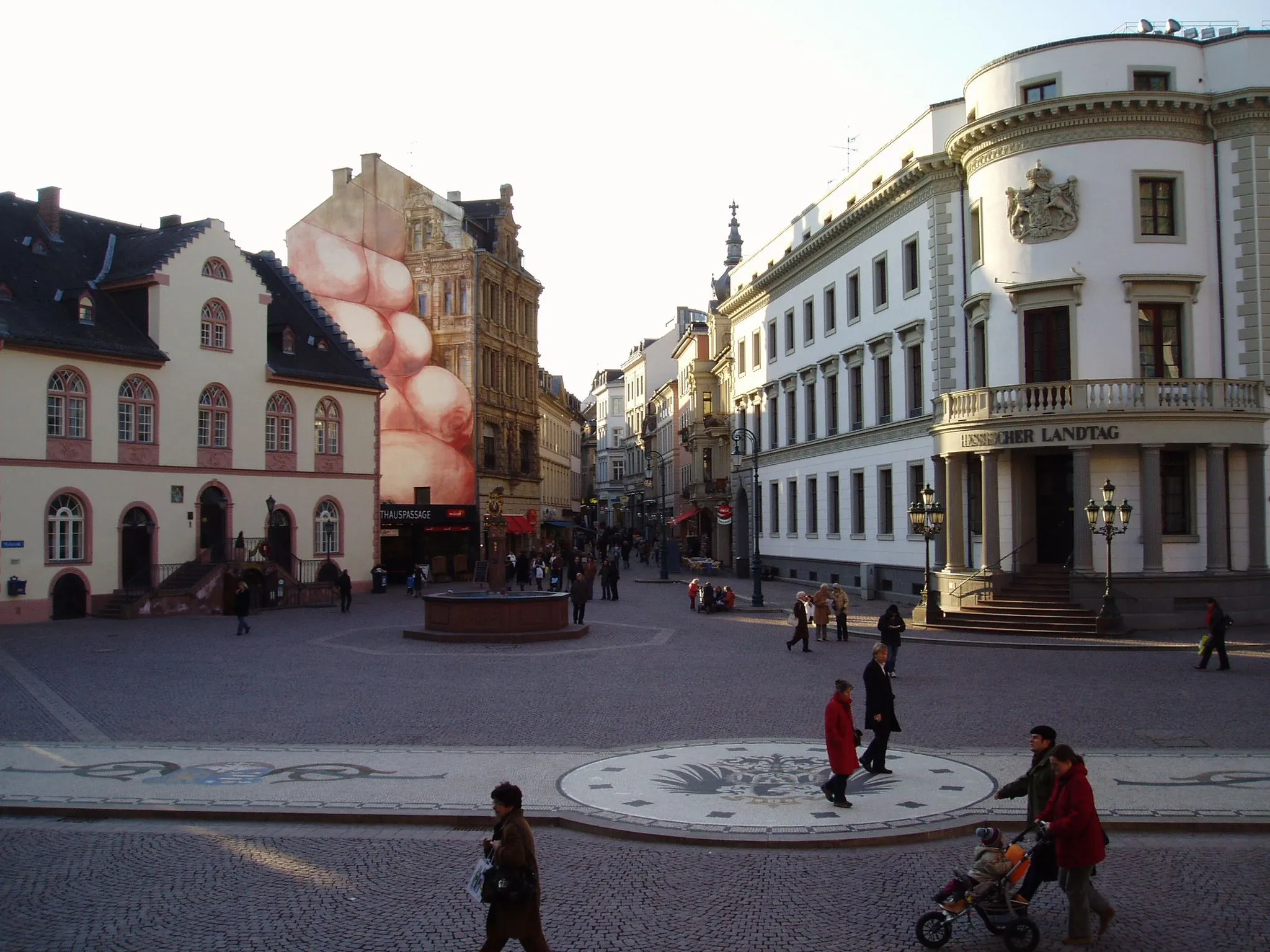 Photo showing: Das Bild zeigt den Schloßplatz in Wiesbaden mit Blick in die Marktstraße. Links das Alte Rathaus, rechts das Stadtschloss, dazwischen der Marktbrunnen. Aufgenommen von den Stufen des Neuen Rathauses.