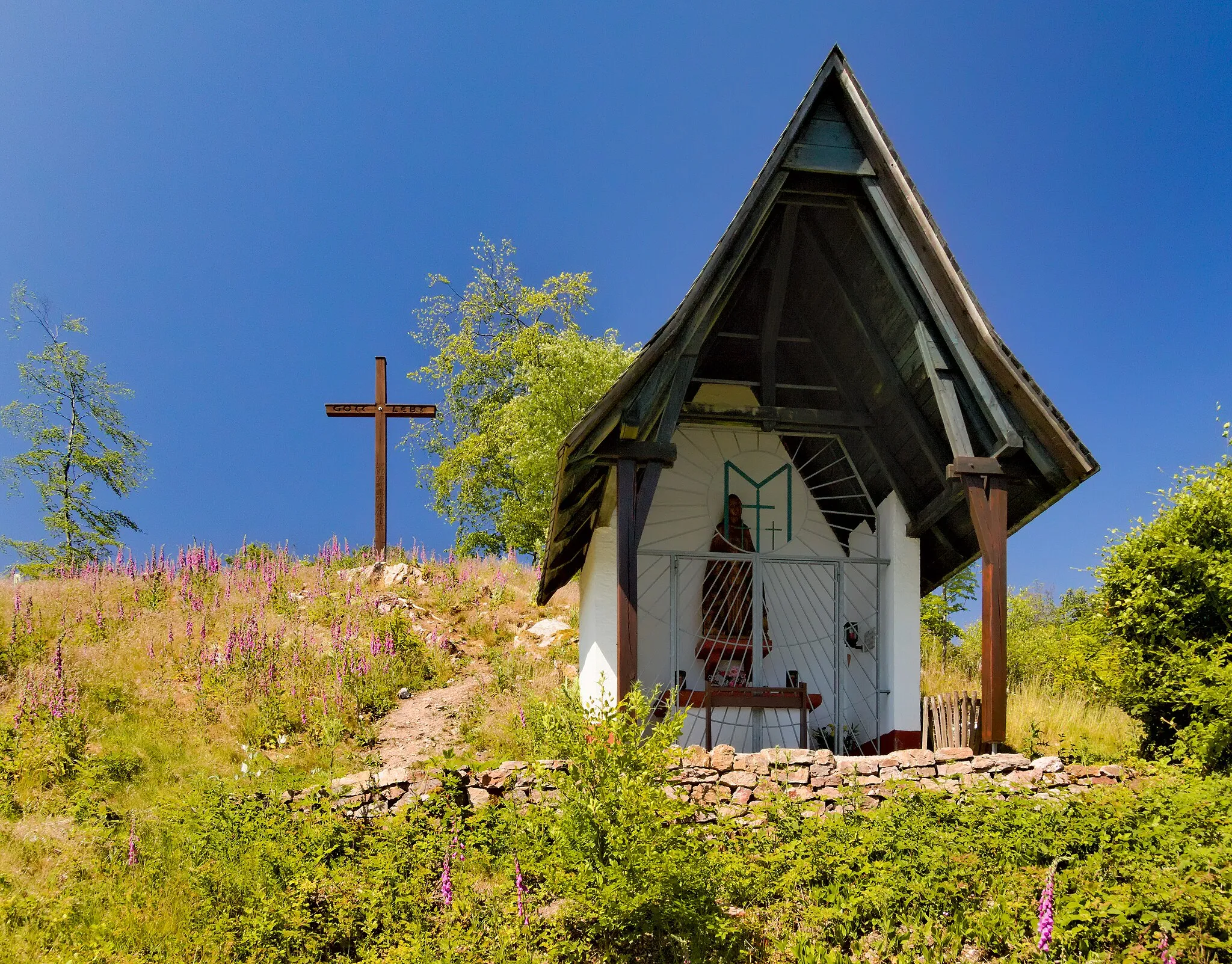 Photo showing: The "Waldkapelle" ("wood chapel") on the mountain Butznickel near Schloßborn (Taunus, Germany) with the "Ostkreuz" ("east cross") in the background. Chapel and cross were built at the beginning of the nineteenfifties on behalf of war refugees from former eastern parts of Germany. In spite of its name the chapel is no longer located in a wood due to the deforestations following the dryness of the years 2018/2019.