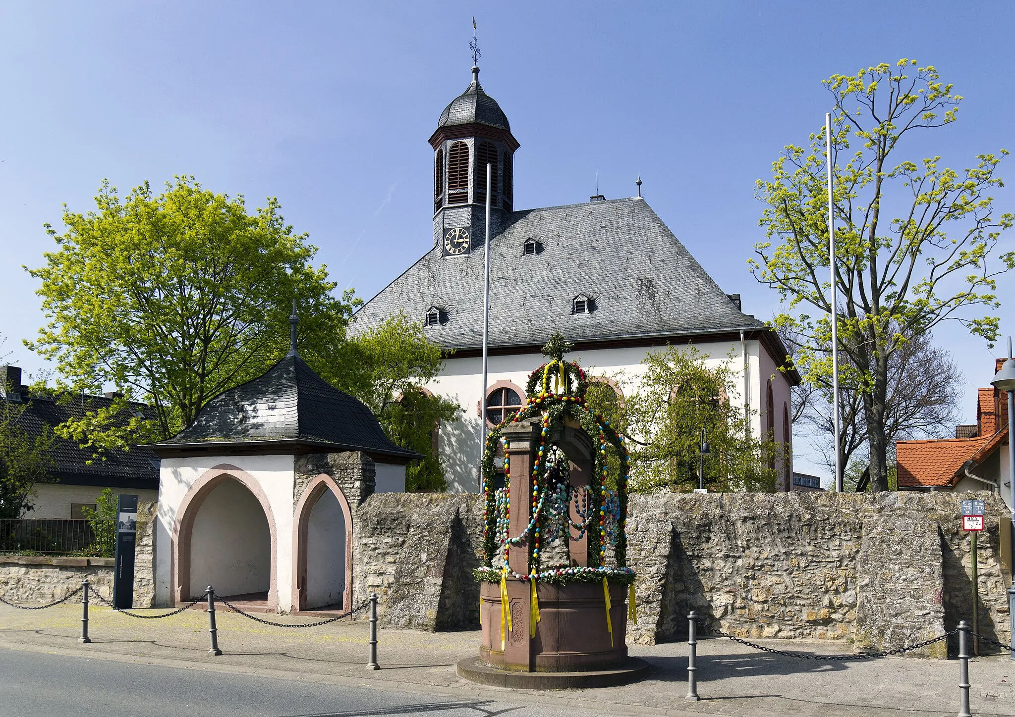 Photo showing: Rüsselsheim, Stadtteil Bauschheim, evangelische Kirche. Im Vordergrund der zur Osterzeit geschmückte Dorfbrunnen