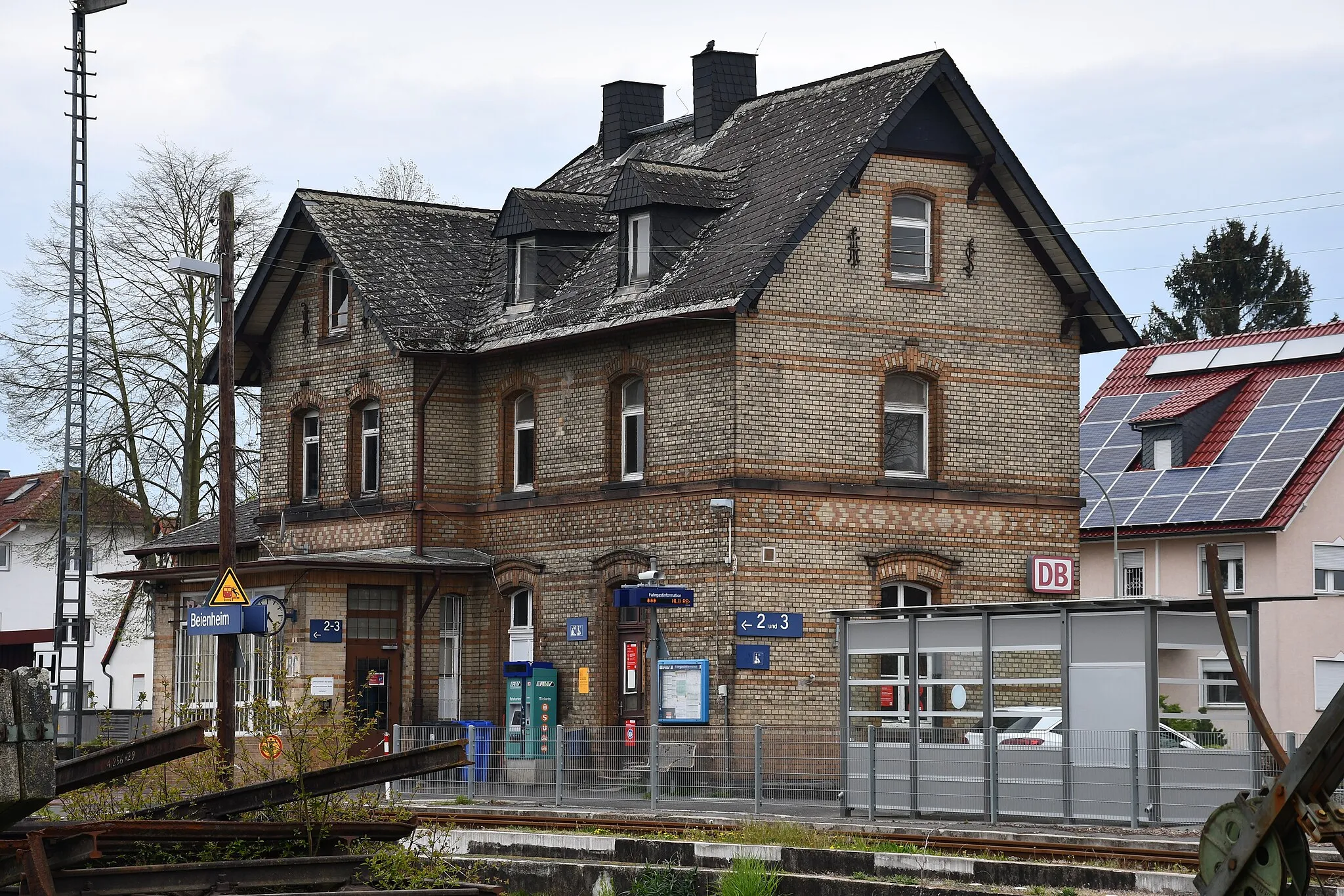 Photo showing: Gleisseite und nördliche Stirnseite des Empfangsgebäudes des Bahnofs Beienheim sowie davorliegende Gleise und Bahnsteige im April 2021, Blick ungefähr aus Nordosten