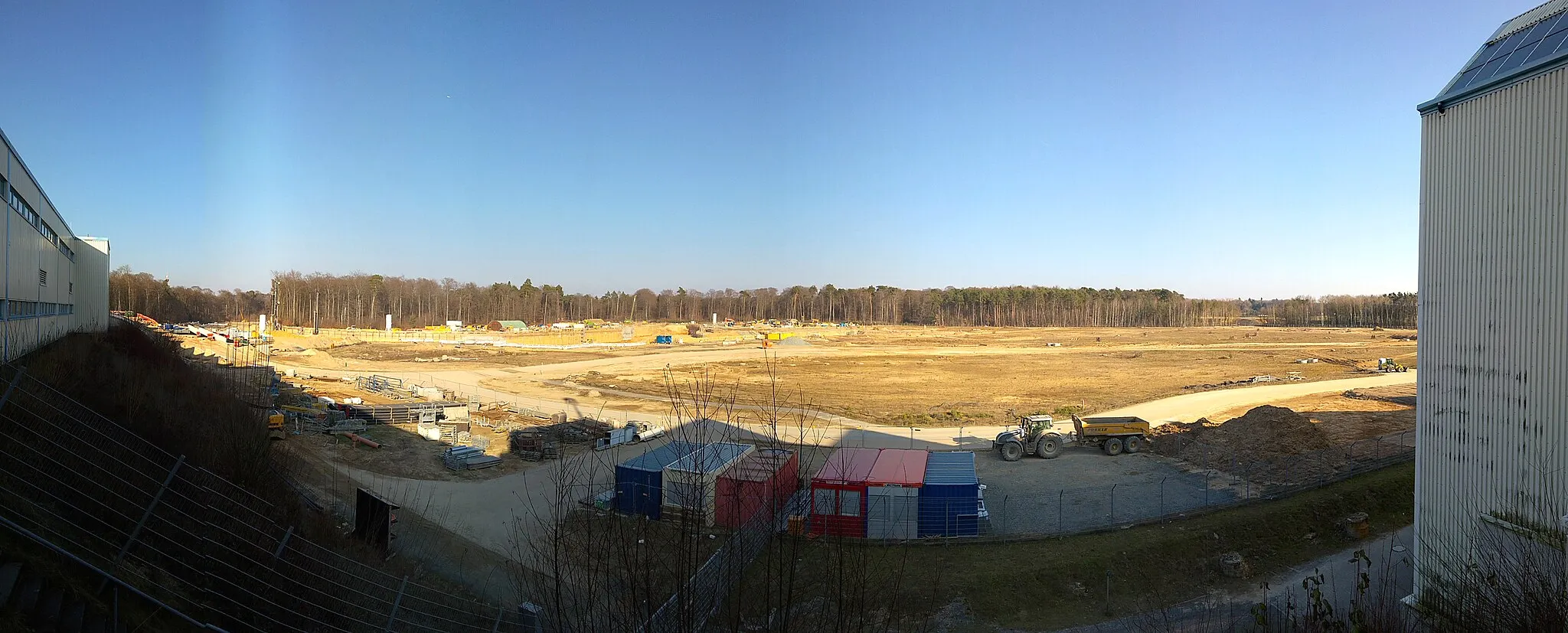 Photo showing: FAIR Baustelle Ende Februar 2018: der große Beschleuniger Ring SIS100 und das große Gebäude, in dem sich später mehrere Beamlines kreuzen werden, sind im Baubeginn.
Panorama von 2/3  der Baufläche.