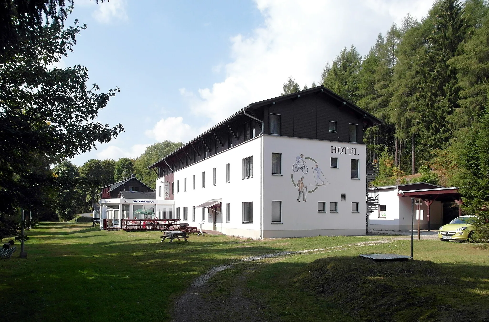 Photo showing: 06.09.2018  01773  Neuhermsdorf (Altenberg Sachs.), Bahnhofstraße 7-8: Bahnhof Hermsdorf-Rehefeld (GMP: 50.732221,13.662442 ) der 1885 eröffneten und 1945 stillgelegten Bahnstrecke Nossen-Moldau (Moldava, Tschechien) im Hirschbachtal. Der deutsche Teil der Bahnstrecke bis Hermsdorf-Rehefeld wurde noch bis 1972 genutzt. Hier das neuere SWF Sporthotel (GMP: 50.732346,13.663187) am Bahnhof. Sicht von Südosten.                                                                                                                                                                                                                               [SAM7333.JPG]20180906310DR.JPG(c)Blobelt