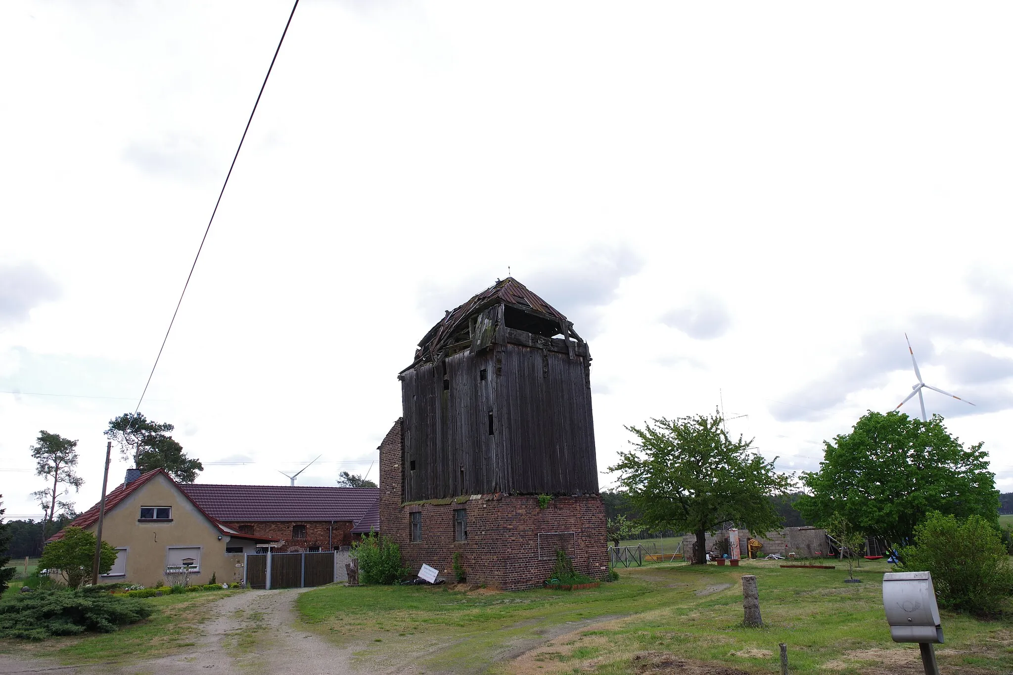 Photo showing: Alte, ehemalige Bockwindmühle im Ort Oelsig. Am Gehöft mit der Nummer 61. Schon stark verfallen. Nach der Google Earth Ansicht, muß wohl 2022 dann der Holzaufbau eingestürzt, oder abgerissen worden sein. Dieser aus Backstein gemauerte Sockel / Untergeschoss wurde wohl 1950 vom damaligen Besitzer errichtet, welcher auch die Technik überarbeitete. Am Anbau ist noch eine schwarze Kanze und darunter mehrere Eisen zu sehen, an welchen man erkennt, das sich dort einmal noch ein zusätzlicher Anbau, vielleicht ein Überdach befand.