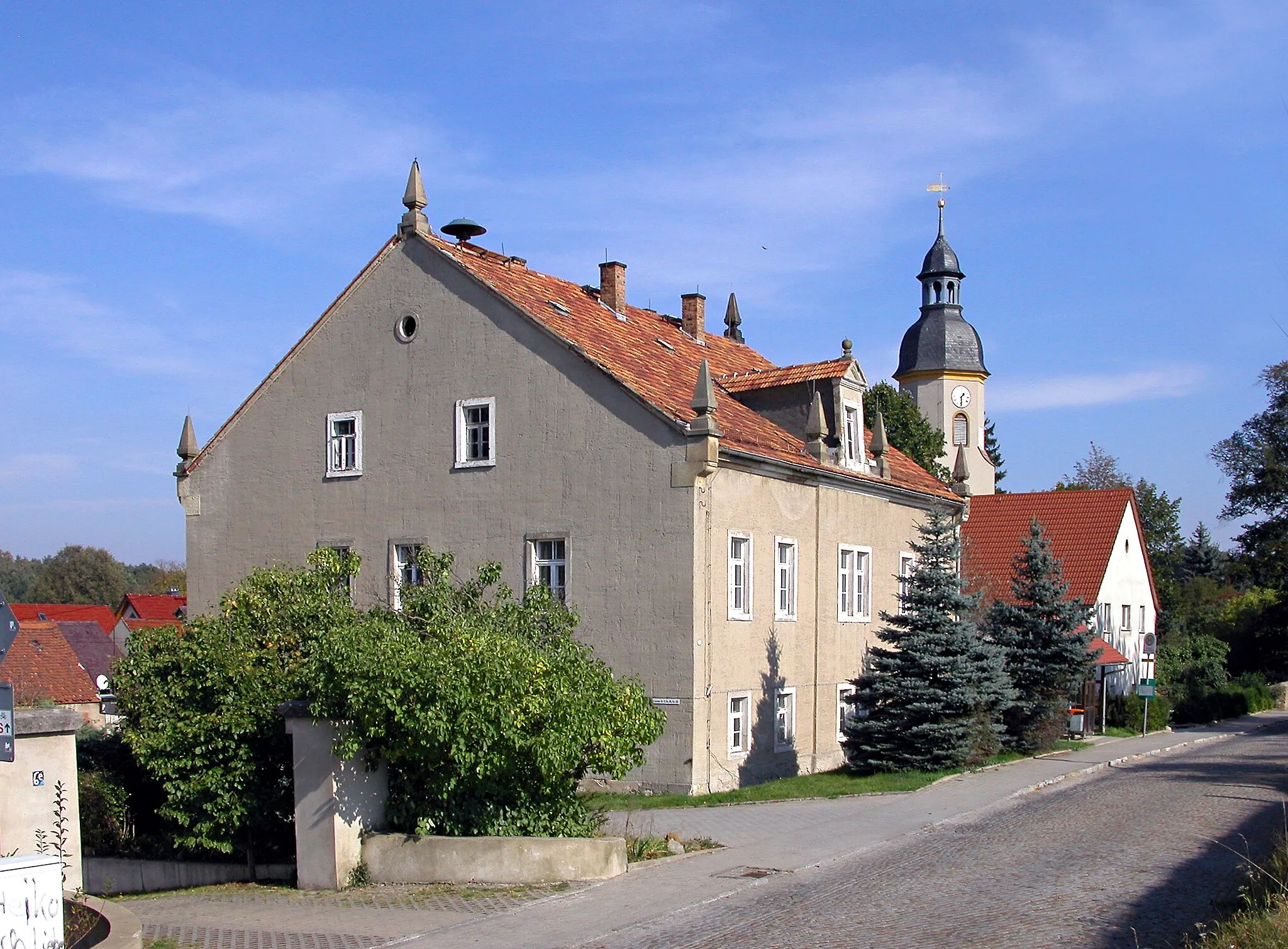 Photo showing: 10.10.2005  01458  Grünberg (Ottendorf-Okrilla), Lausaer Straße 6: Rittergut Grünberg, Herrenhaus (GMP: 51.162517,13.841888) von Südwesten. 1413 Ersterwähnung. Heutiges Herrenhaus nach Brand von 1884 errichtet. Das Rittergut wurde 1945 aufgeteilt, in den Scheunen und Stallungen richtete man Wohnungen ein. In der DDR-Zeit war im Erdgeschoß des Herrenhaus war eine Arzstation und bis 1994 die Gemeindeverwaltung. Im Hintergrund die barocke Dorfkirche.                         [DSCN7697.TIF]20051010055DR.JPG(c)Blobelt