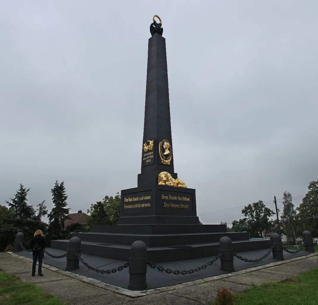 Photo showing: Arbesau (Varvažov): Blick auf das österreichische Denkmal in Erinnerung an die Schlacht bei Kulm 1813. Das Denkmal wurde 1825 nach einem Entwurf von Oberstleutnant Ourlandie errichtet wurde. Es handelt sich um einen gusseisernen Obelisk, dessen Teile in der Eisenhütte Neujoachimsthal (Nový Jáchymov) gegossen wurden. Mit einem Gewicht von 113 Tonnen und einer Höhe von 17 Metern handelt es sich um das bedeutendste Gusswerk der Hütte. Das Denkmal ist dem österreichischen General Hieronymus von Colloredo-Mansfeld (1775-1822) gewidmet, der hier am 17. September 1813 die Franzosen zum zweiten Male schlug. Das Denkmal krönt ein Doppeladler mit Lorbeerkranz. Bildhauer war Wenzel Prachner aus Prag.