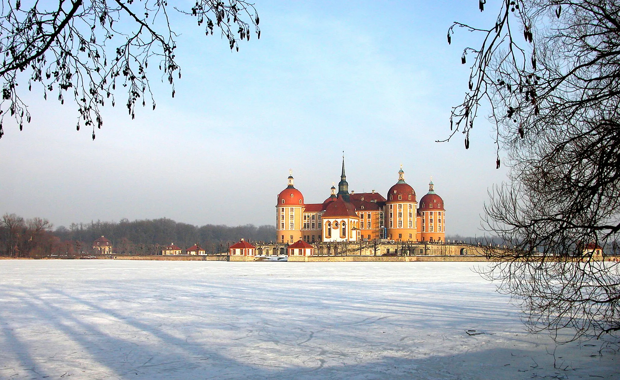 Photo showing: 30.01.2006  01468  Moritzburg, Schloßallee: Barockes Wasserschloß (GMP: 51.167547,13.679459), 1542-1546 hervorgegangen aus einem Jagdhaus. Planung und Ausführung durch Caspar Voigt von Wierandt und Hans von Dehn-Rothfelser. Um 1660 wurde die Schloßkapelle von Wolf Caspar von Klengel angefügt. 1723-1736 Aufstockung, Erweiterung und Umgestaltung durch Matthäus Daniel Pöppelmann. Moritzburg war bis 1918 königliches Jagdrevier. Nach der gesetzlich geregelten Fürstenabfindung wurde der Grundbesitz in Moritzburg 1924 dem ehemaligen Königshaus übertragen. 1945 folgte dann jedoch die Enteignung. 1947 Eröffnung des Barockmuseums Schloß Moritzburg.  Sicht von Westen über den vereisten Schloßteich zur Kapelle.                                                                                                                                                      [DSCN8604.TIF]20060130010DR.JPG(c)Blobelt