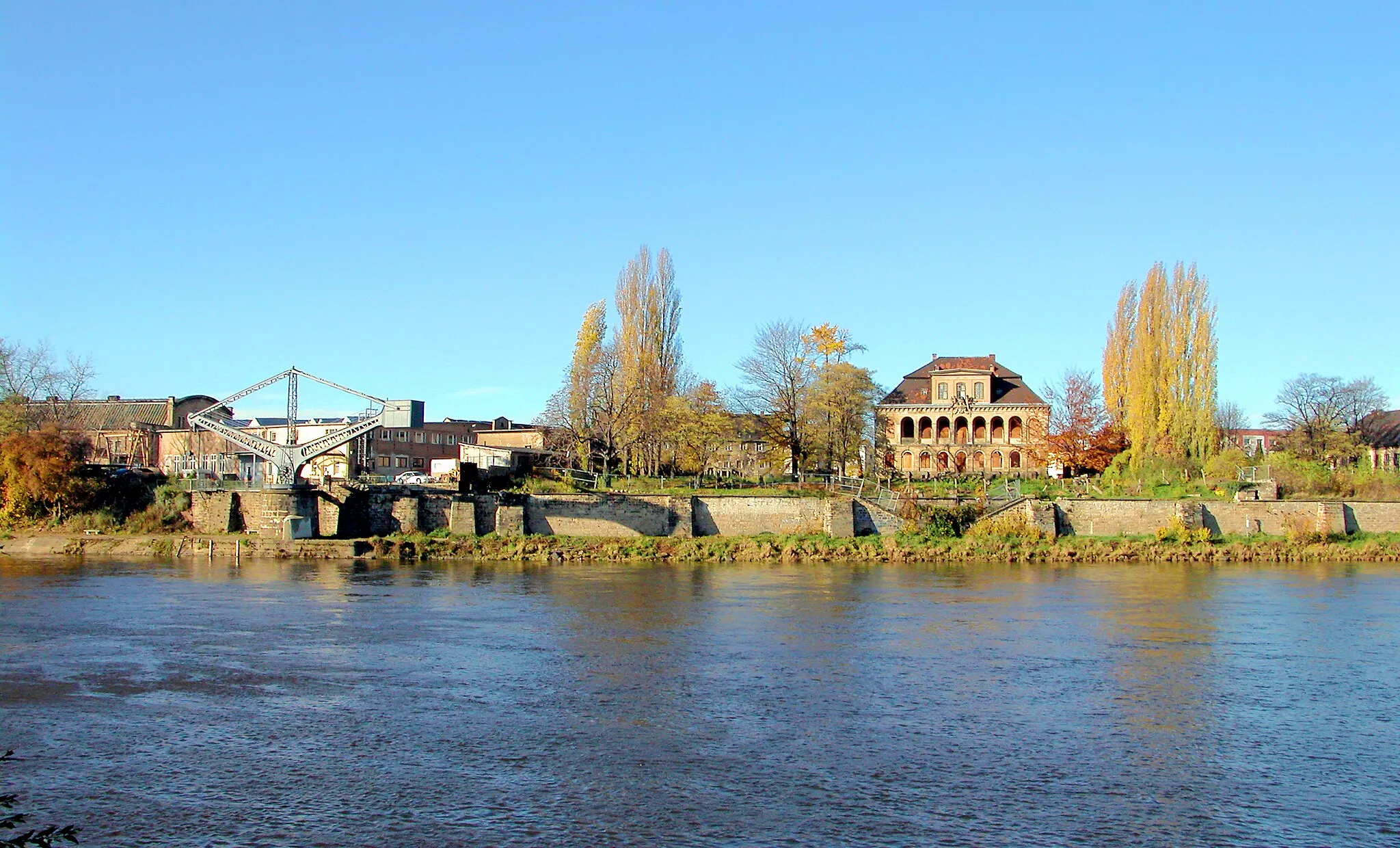 Photo showing: 15.11.2006   01139  Dresden-Übigau: Blick über die Elbe zum Schloß Übigau, Rethelstraße 45 (GMP: 51.069425,13.698808). Johann Friedrich Eosander von Göthe errichtete 1724-1726 das Gebäude für Feldmarschall Graf Jacob Heinrich von Flemming. Hinter ihm stand August der Starke (1670-1733), das Anwesen sogleich kaufte. Von der einstigen Pracht ist nicht viel geblieben. Die Maschinenbauanstalt zu Übigau kaufte 1836 das Schloß und errichtete gleich nebenan eine Dampfmaschinenfabrik. Im Schloß wohnte und arbeitete Andreas Schubert (1808-1870), der den ersten Passagierdampfer "Königin Maria" und die erste deutsche Dampflokomotive, die "Saxonia", konstruierte. Aus dem traditionsreichen Betrieb ging nach 1945 der VEB Dampfkesselbau hervor. Links der alte Uferkran von 1891 (GMP: 51.068506,13.699374) vor der Schiffswerft Übigau.                                                                                                                                                                                                                                                                                         [DSCN12710.TIF]20061115075DR.JPG(c)Blobelt