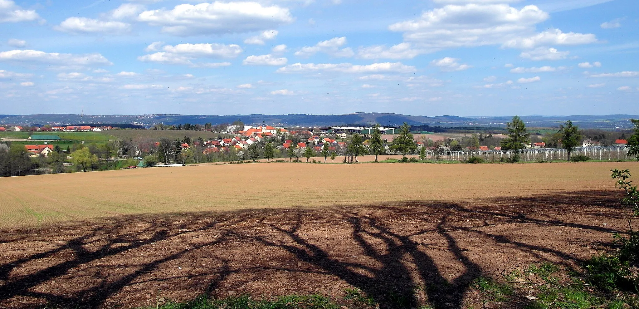 Photo showing: 08.05.2021   01809  Röhrsdorf (Dohna): Blick von der "Röhrsdorfer Aussicht" (GMP: 50.959996,13.801352) am oberen Rand des Schloßparks Röhrsdorf nach Nordosten auf den Ort, das Schloß (GMP: 50.965573,13.807929) und die Obstlagerhallen der Obstproduktion 
Borthen (Erzeugerorganisation Dresdner Obst EG) in Röhrsdorf. Am Horizont das Schönfelder Hochland nordöstlich von Dresden u.a. mit dem Borsberg.                                                                                                             [SAM4633.JPG]20210508100DR.JPG(c)Blobelt