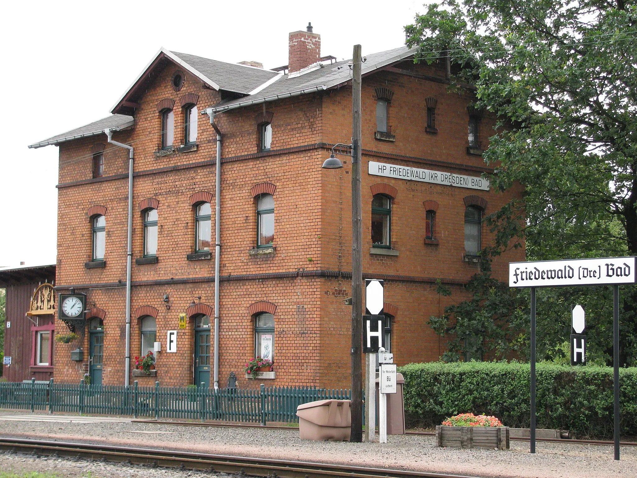 Photo showing: Haltepunkt Friedewald Bad der Lößnitzgrundbahn, in Dippelsdorf im Ortsteil Friedewald, Gemeinde Moritzburg, Sachsen. Schwach lesbar ist am Gebäude (zwischen EG und 1. Stock über der Eingangstür) noch der bis 1940 gültige Bahnhofsname Dippelsdorf.