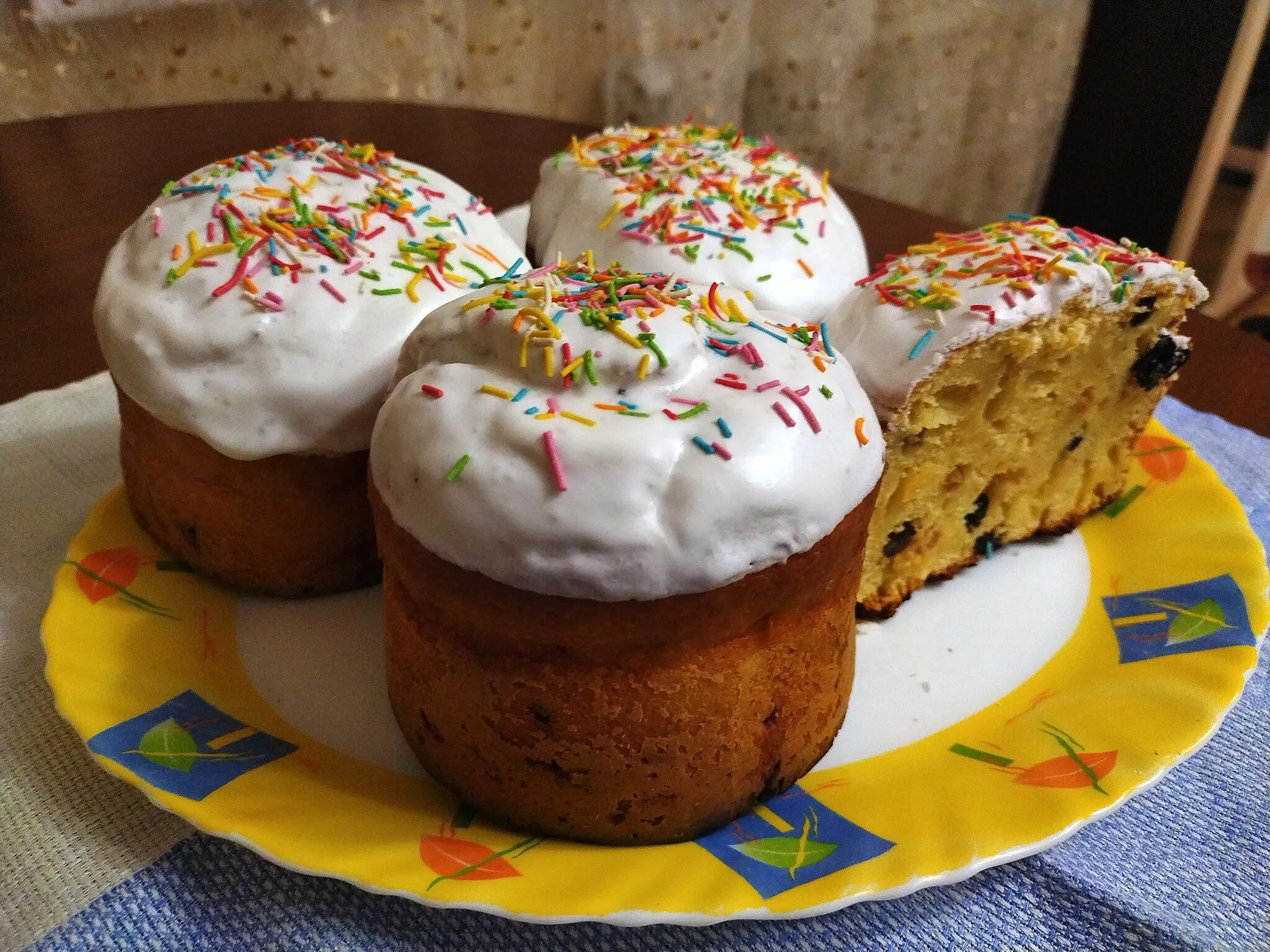 Photo showing: Kulich, a type of traditional Easter bread from Russia, made in a cylindrical shape, with frosting and coloured sugar on top. The dough usually contains raisins, dried apricots, candied fruits, and such. The photo represents kulichi (plural form of 'kulich') baked according to a monastery recipe, which also requires cognac, cardamom, and tvorog (Eastern European cottage cheese).