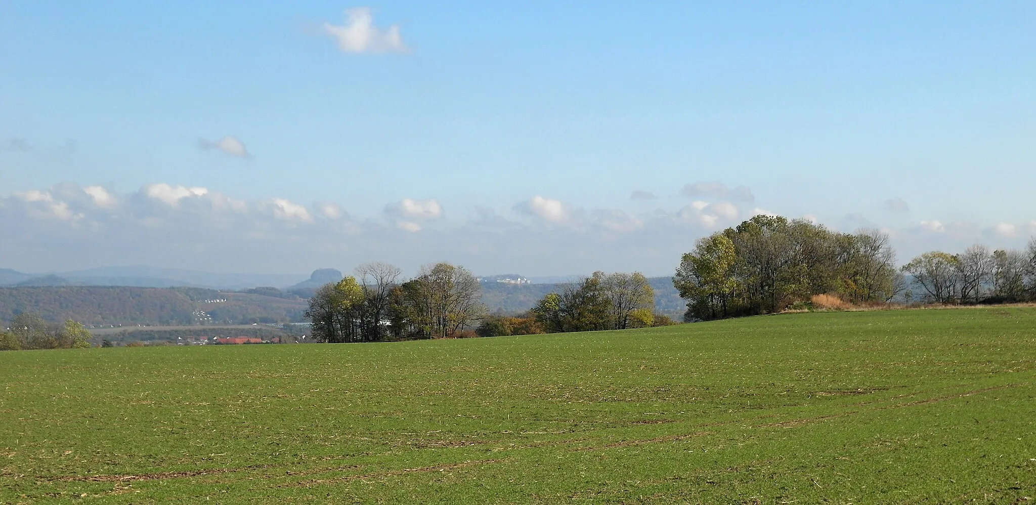 Photo showing: 07.11.2019   01809  Burkhardswalde (Müglitztal): Eingestreut in die Äcker auf dem Burkhardswalder Plateau befinden sich etliche baumbewachsene Kleinkuppen  im Areal von (GMP: 50.918900,13.873515). Blick nach Osten bis in die Sächsische Schweiz mit Lilienstein (links) und der Festung Königstein (rechts.).                                                                                                                                                                                                 [SAM1771.JPG]20191107340DR.JPG(c)Blobelt