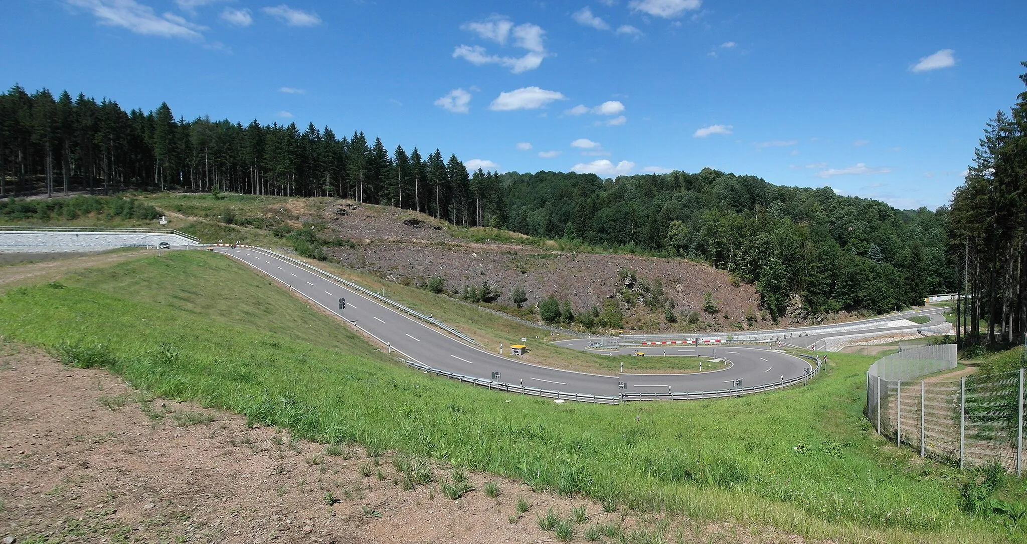 Photo showing: 26.07.2015     01768  Glashütte:  Neues Hochwasserrückhaltebecken Glashütte Prießnitztal (2009-2013). Talseite mit neuer Serpentinenstraße. Steinschüttdamm (GMP: 50.844609,13.754744), Wasseroberfläche gefüllt: 11,1 ha, Speicherraum:	1,05 Mio m³, Baukosten 26 Millionen Euro.                                                                                                                                   [SAM1202+1204.JPG]20150726020MDR.JPG(c)Blobelt