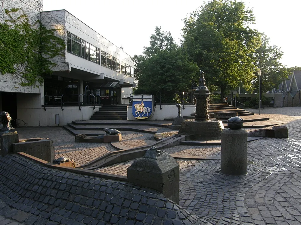 Photo showing: der Brunnen vor der St. Aldegundis in Büttgen-Kaarst und Rathaus im Abendlicht