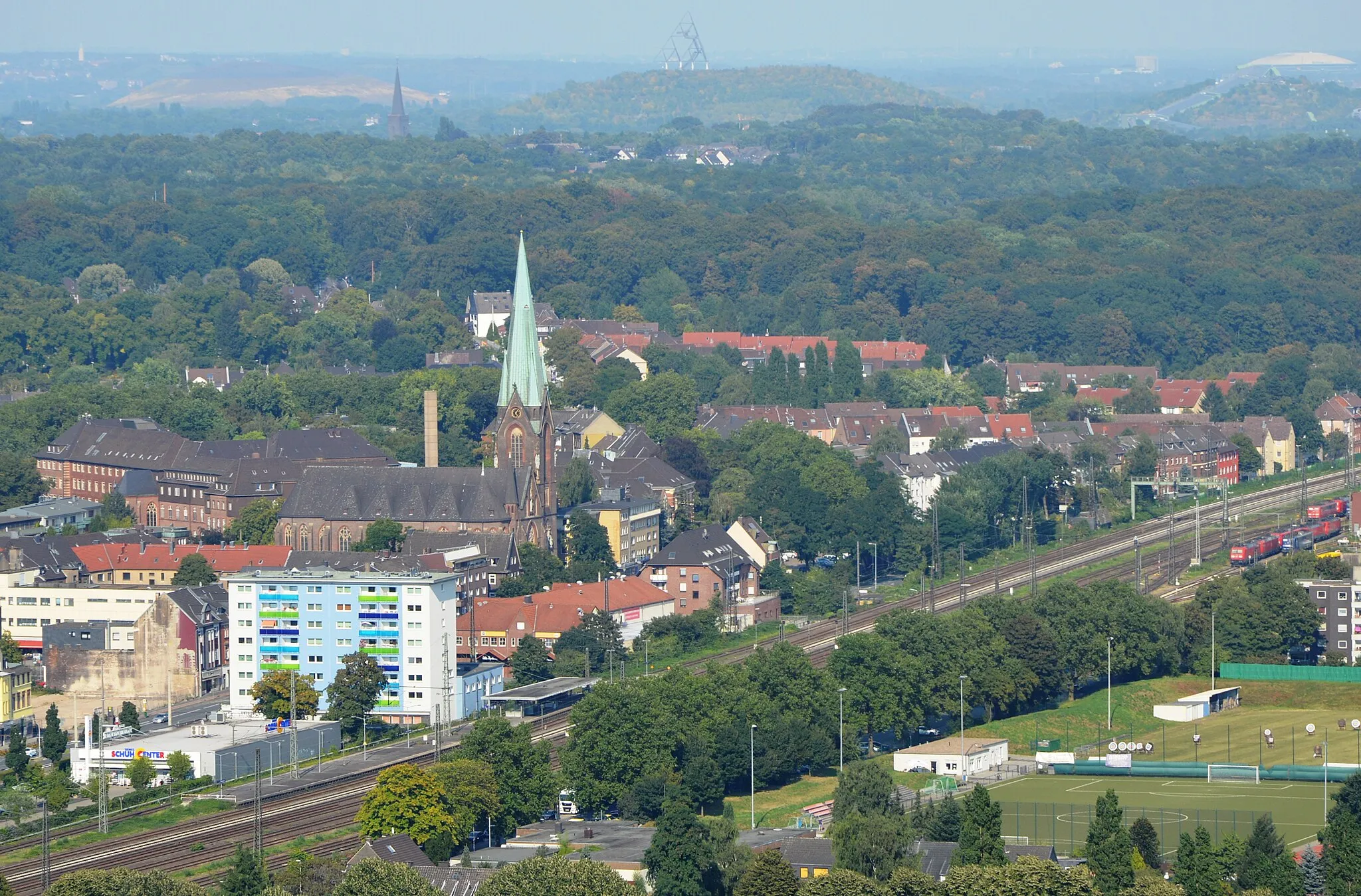 Photo showing: Blick auf Oberhausen-Osterfeld mit der Pfarrkirche St. Pankratius und dem Bahnhof Oberhausen-Osterfeld. Das bunte Gebäude ist ein Wohnhaus der GE-WO. Im Hintergrund der Tetraeder (Bottrop).