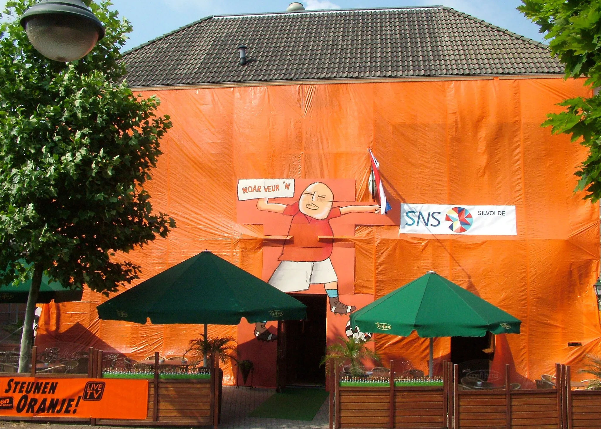 Photo showing: Anlässlich der Fußball-Europameisterschaft 2008: Kneipe in Silvolde, mit der niederländischen Nationalfarbe Orange verhüllt. Sprechblase im niedersächsischen Dialekt: "Nach vorn".