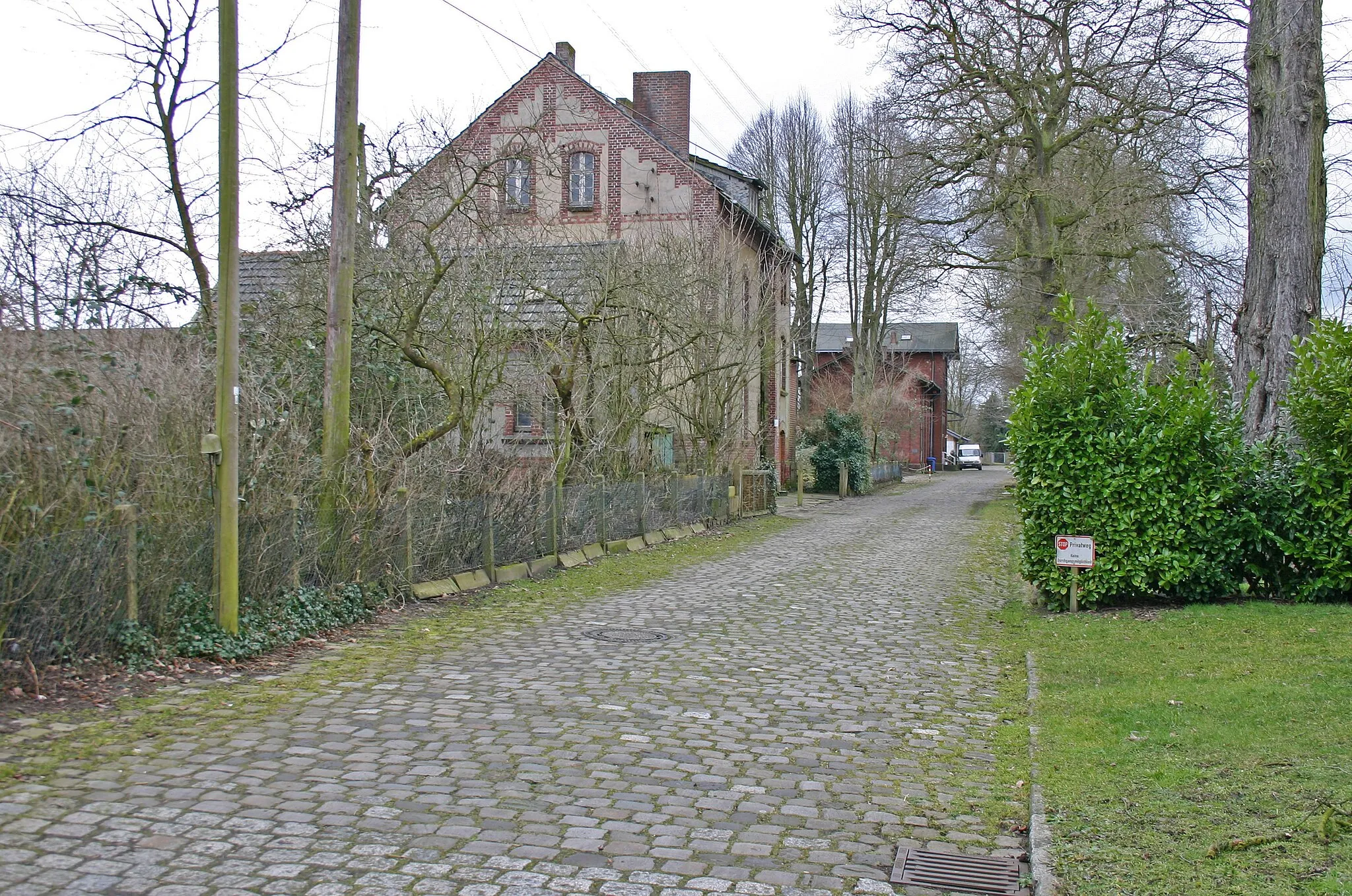 Photo showing: Bahnhofstraße in Drevenack: Vorn links das ehemalige Bahnmeister-Wohnhaus, dahinter verdeckt das ehemalige Empfangsgebäude. Die Straßenpflasterung stammt teilweise noch aus der Eröffnungszeit um 1874/75.