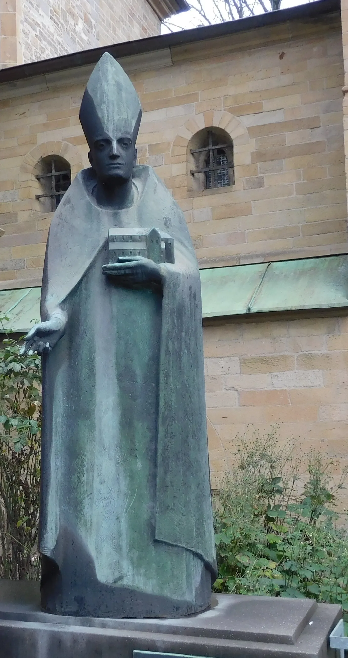 Photo showing: Figure in medival style with a modell of the first Münster in his left hand.