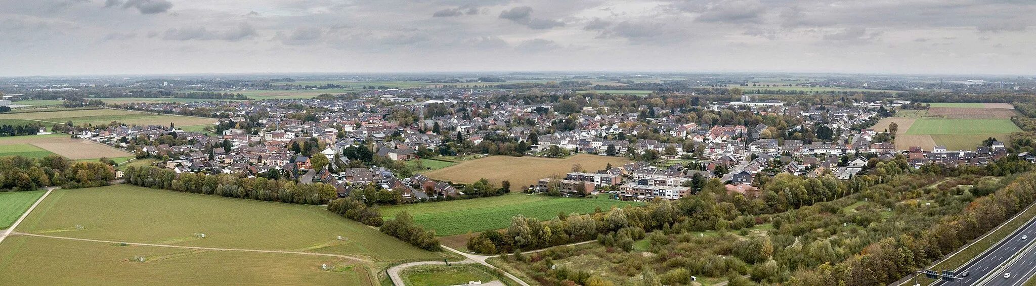 Photo showing: Hochneukirch liegt südlich von Mönchengladbach und grenzt unmittelbar nördlich an das Braunkohletageabbaugebiet von Garzweiler an. Nachbarorte von Hochneukirch fielen der Braunkohle zum Opfer. Die Aufnahme entstand aus 100 Metern Höhe als kleines Panorama.
