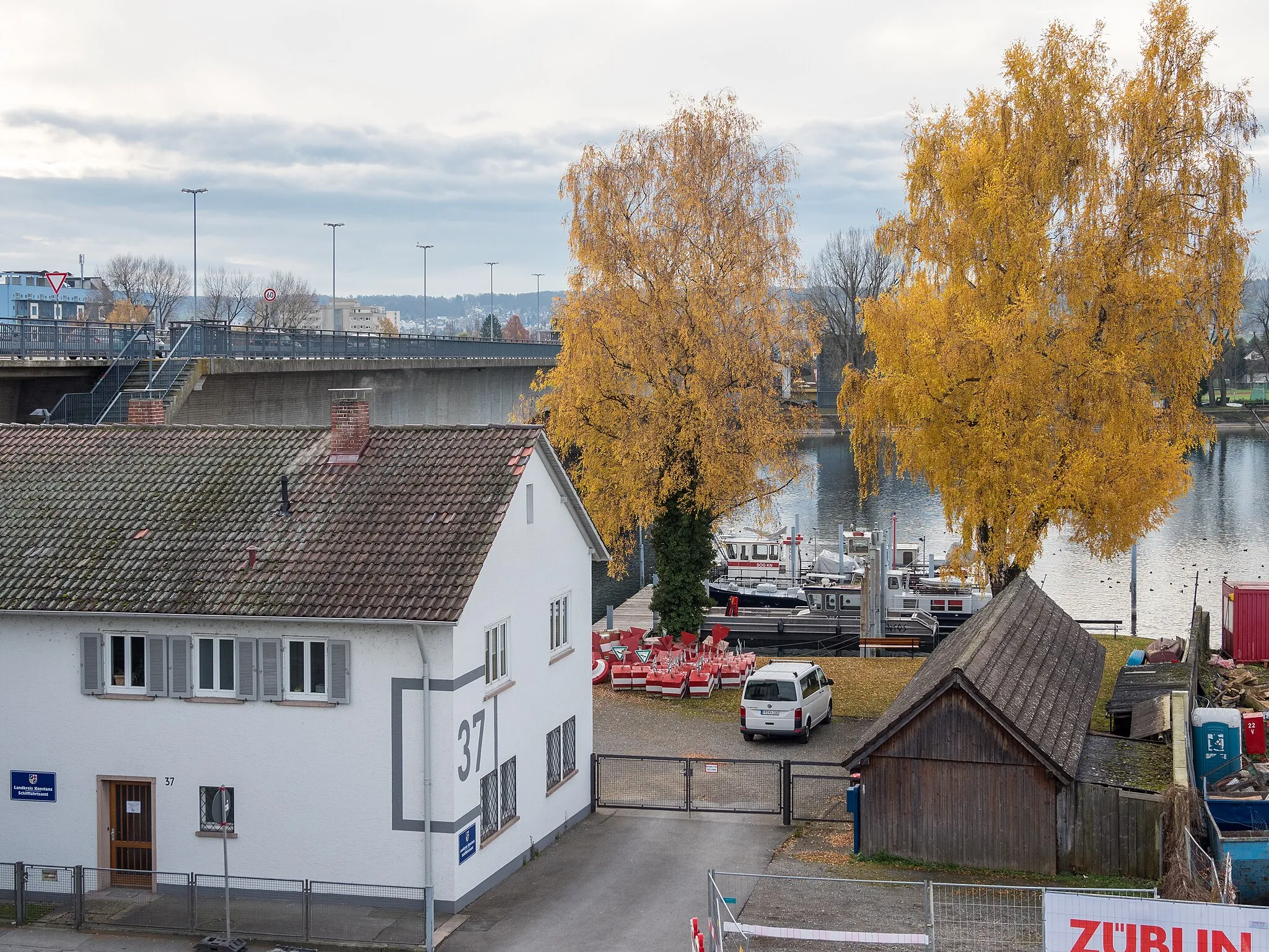 Photo showing: Konstanz, Reichenaustrasse 37: Schifffahrtsamt des Landkreises Konstanz neben der Schänzlebrücke. Im Hof lagern "Naturschutzgebiet"-Bojen, auf dem Rhein liegen Dienstboote.