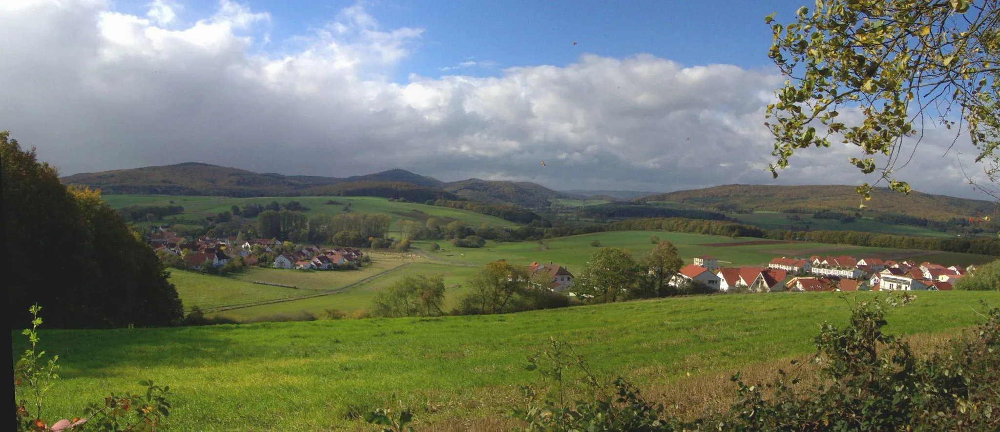 Photo showing: Blick von Michelbach auf die östlichen Damshäuser Kuppen (von links:) Hungert (412 m), Rimberg (498 m), Feiselberg (zweigipfelig, 413 m) und Roßberg (425 m). Mittig im Hintergrund die Gipfel des Breidenbacher Grundes mit Nimerich (533 m), Schwarzenberg (561 m) und Heppenberg (577 m). Der breite, 474 m hohe Wollenberg (rechts) ist der östlichste Ausläufer des Rothaargebirges, in das die beiden erwähnten Gebirgszüge nach Norden, jenseits der Lahn, übergehen.