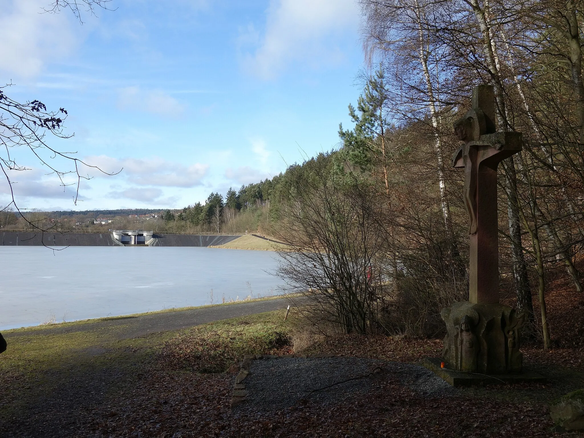 Photo showing: Das Haunesee-Kreuz am Haunestausee (auch Haunetalsperre oder Haunesee genannt) bei Marbach im Landkreis Fulda, im Hintergrund der Staudamm. Das Kreuz, geschaffen von Johannes Kirsch aus Petersberg, wurde im Jahr 1992 aufgestellt.