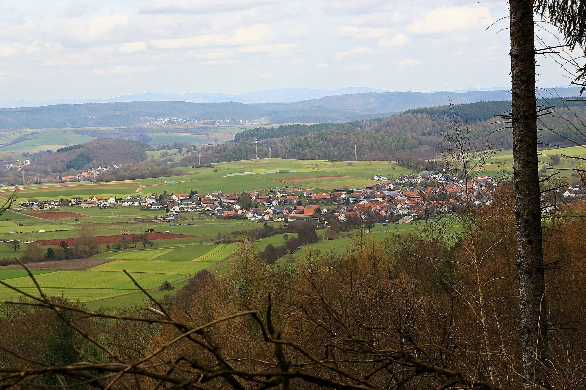 Photo showing: Warzenbach, Stadtteil von Wetter (Hessen). Im Hintergrund Mellnau am Rand des Burgwald. In der Ferne dahinter das Hohe Lohr mit dem Fernmeldeturm. Ansicht von Südwesten (vom Homberg).
