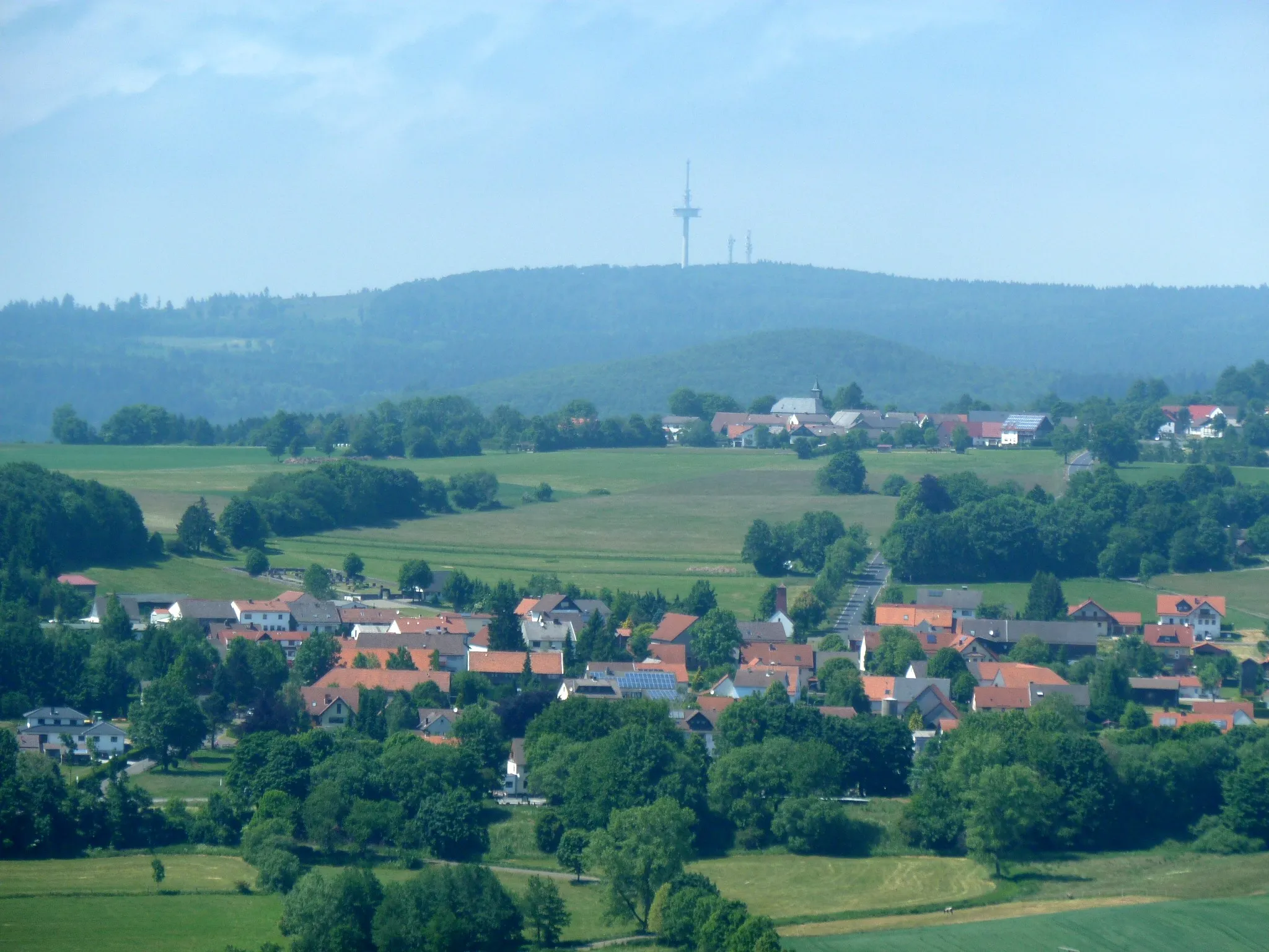 Photo showing: View from Turbine No. 7 in the "Windenergiepark Vogelsberg" wind farm near Hartmannshain (Hesse, Germany). Hartmannshain lies in the foreground. Herchenhain and the Hoherodskopf (with telecommunications tower) are visible in the background.