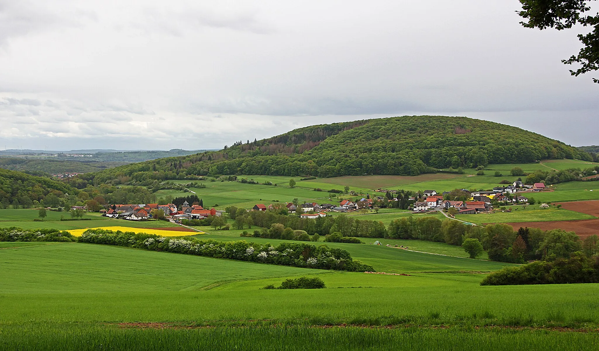 Photo showing: Dilschhausen mit dem ehemaligen Unterdorf (links) und Oberdorf (rechts). Ansicht von Nordwesten. Im Hintergrund der Auersberg sowie Elnhausen, Marburg-Stadtwald und der Frauenberg (370 m).