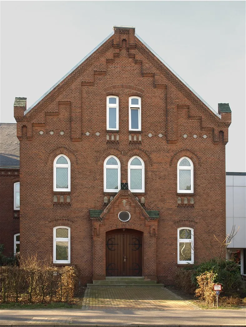 Photo showing: Tornesch - Esinger Road 102 - Johannes Schwennesen School - Right gable - Year Built: 1906 - Photo by 2008
- The school was built in 1906, after the old school (at Alter Schulweg) had become too small. It is a brick building in neo-Gothic style. The horseshoe-shaped floor plan is oriented so that two gables point to the street. In the right wing was the Esinger church hall, which was equipped with pews, pulpit and chandeliers. At the entrance portal and the shape of the windows, the former sacral use can still be seen. From 1959 - after the construction of the church (Jürgen-Siemsen-Straße 28) - the school used the former church hall. In 2007, the hall was again made largely original.