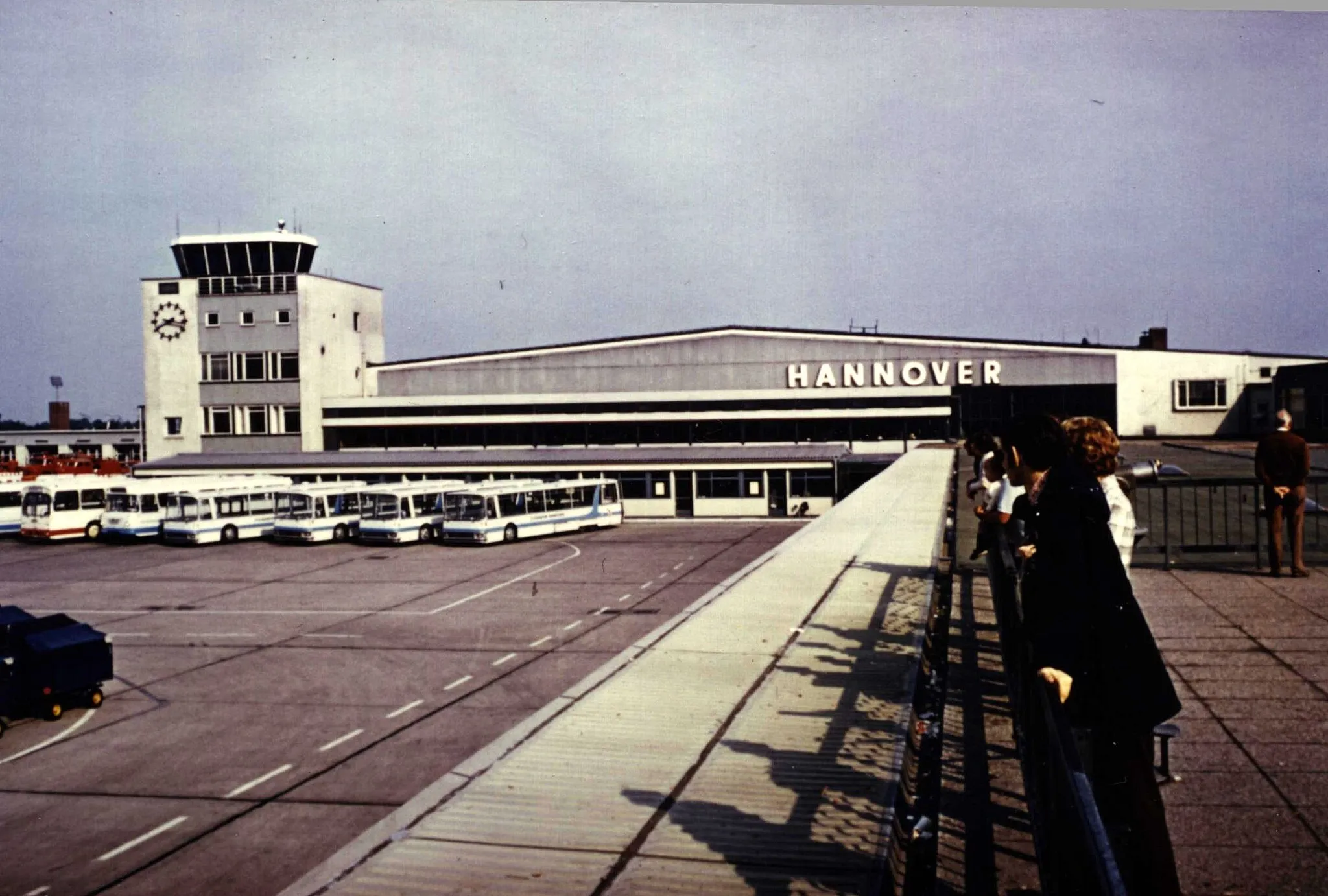 Photo showing: Der Flughafen Hannover-Langenhagen im Jahr 1970. Blick von der Aussichtsterasse auf das Vorfeld mit Zubringerbussen. Links der Kontrollturm, rechts die Abfertigungshalle.