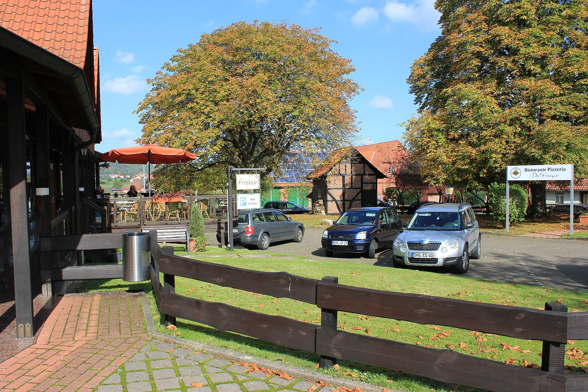 Photo showing: Dieses Bild zeigt den Dorfkern der Gemeinde Luhden mit dem Kastanienhof und den charakteristischen Kastanienbäumen. Links sieht man die Luhdener Ladenzeile.