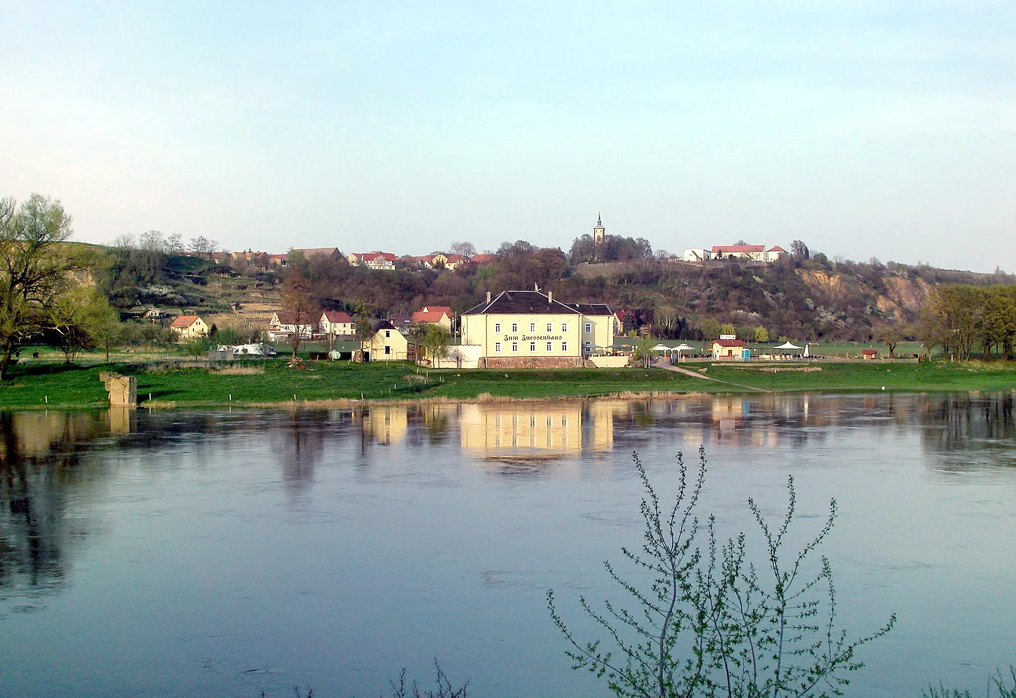 Photo showing: 10.04.2009  01665  Zadel (Diera-Zehren): Blick von Zehren über die Elbe nach Zadel. Im Vorgergrund das "Zum Zuessenhaus" (GMP: 51.195006,13.419016), Elbstraße 10. Auf dem Hochufer der Ort Zadel mit der St.-Andreas-Kirche Zadel (GMP: 51.196776,13.428570) Rechts davon das ehemalige Kammergut. Links der Kirche das Gehöft vom Weingut Schloß Proschwitz, Dorfanger 19, Zadel (GMP: 51.197541,13.427995).                                                                                                                           [DSCN36273]20090410830DR(c)Blobelt