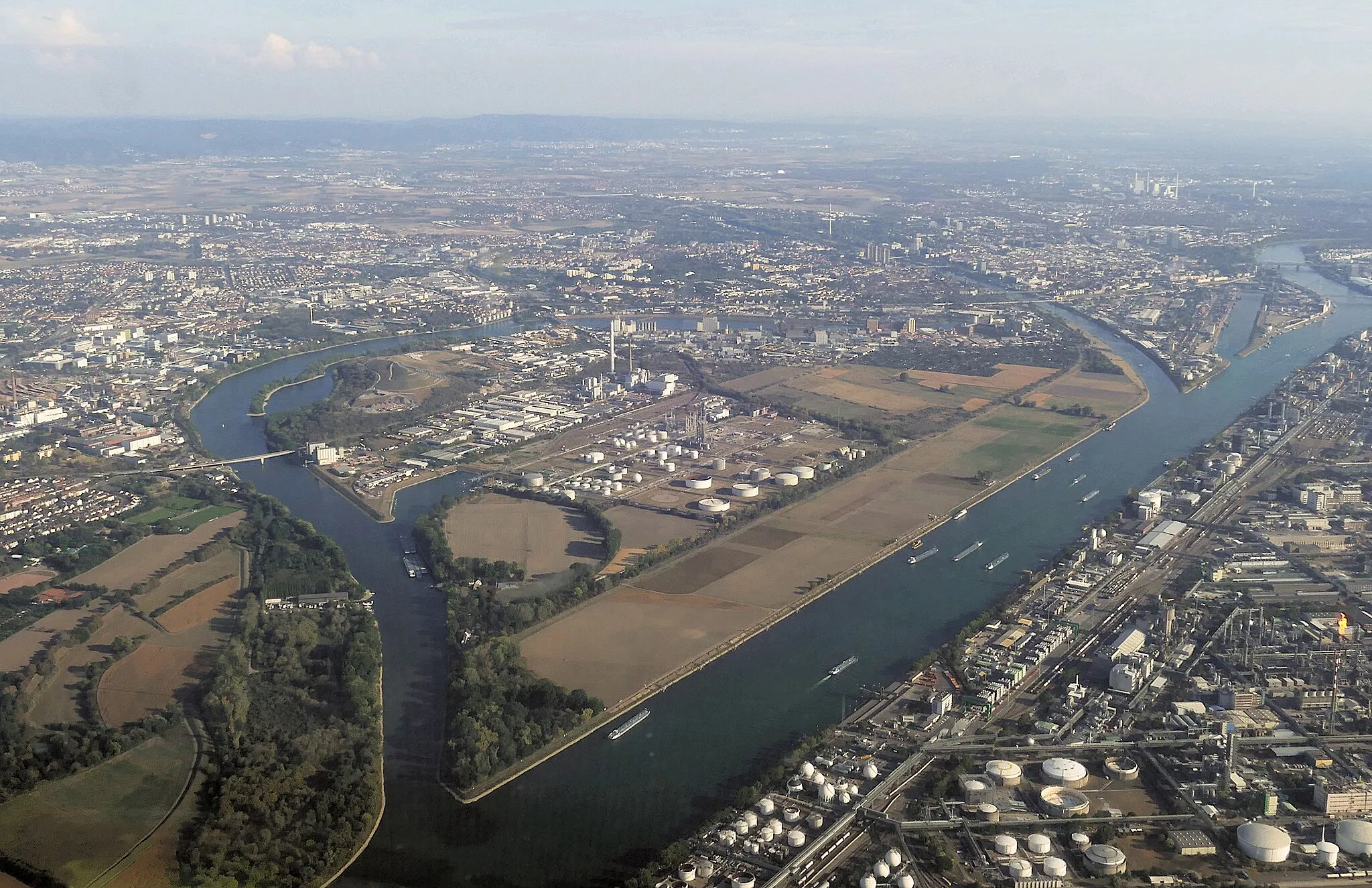 Photo showing: Aerial view of Friesenheim Island from northwest to southeast, taken from a gyrocopter. To the west of the Rhine (bottom right in the picture), part of the BASF factory site in Ludwigshafen can be seen. Flaring is visible there.