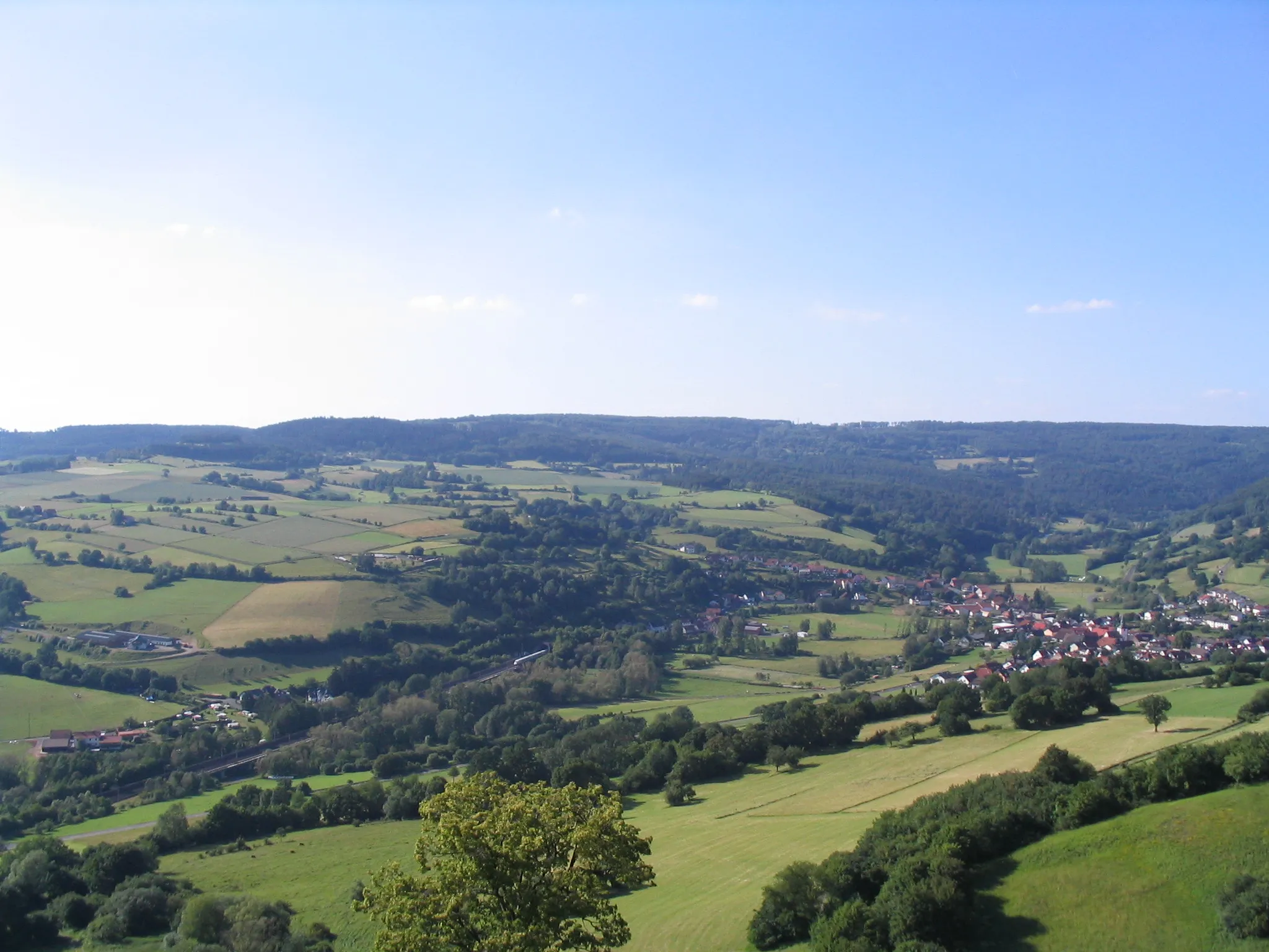 Photo showing: Blick von der Burg Schwarzenfels in das Sinntal mit dem Ort Weichersbach und dem Südportal des Landrückentunnels. Im Hintergrund der Höhenzug "Breite First" (550 m)