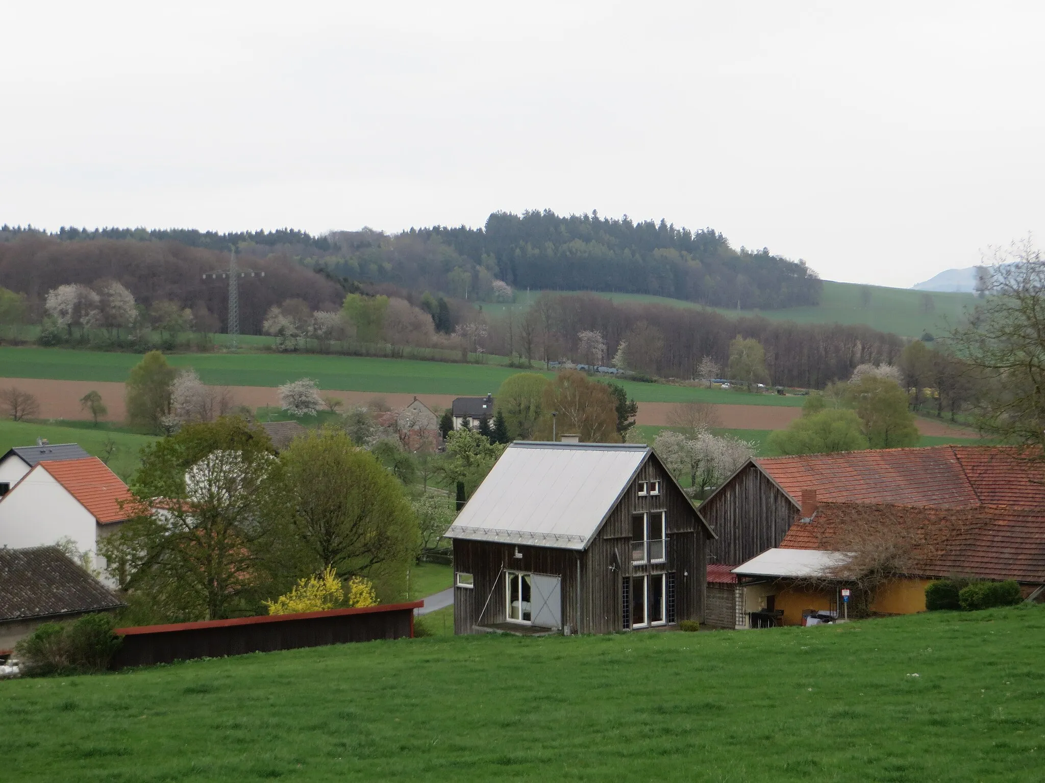 Photo showing: Blick über die Häuser von Öttersbach südsüdostwärts auf eine namenlose Erhebung bei Hausfürst. Milseburger Kuppenrhön, Landkreis Fulda