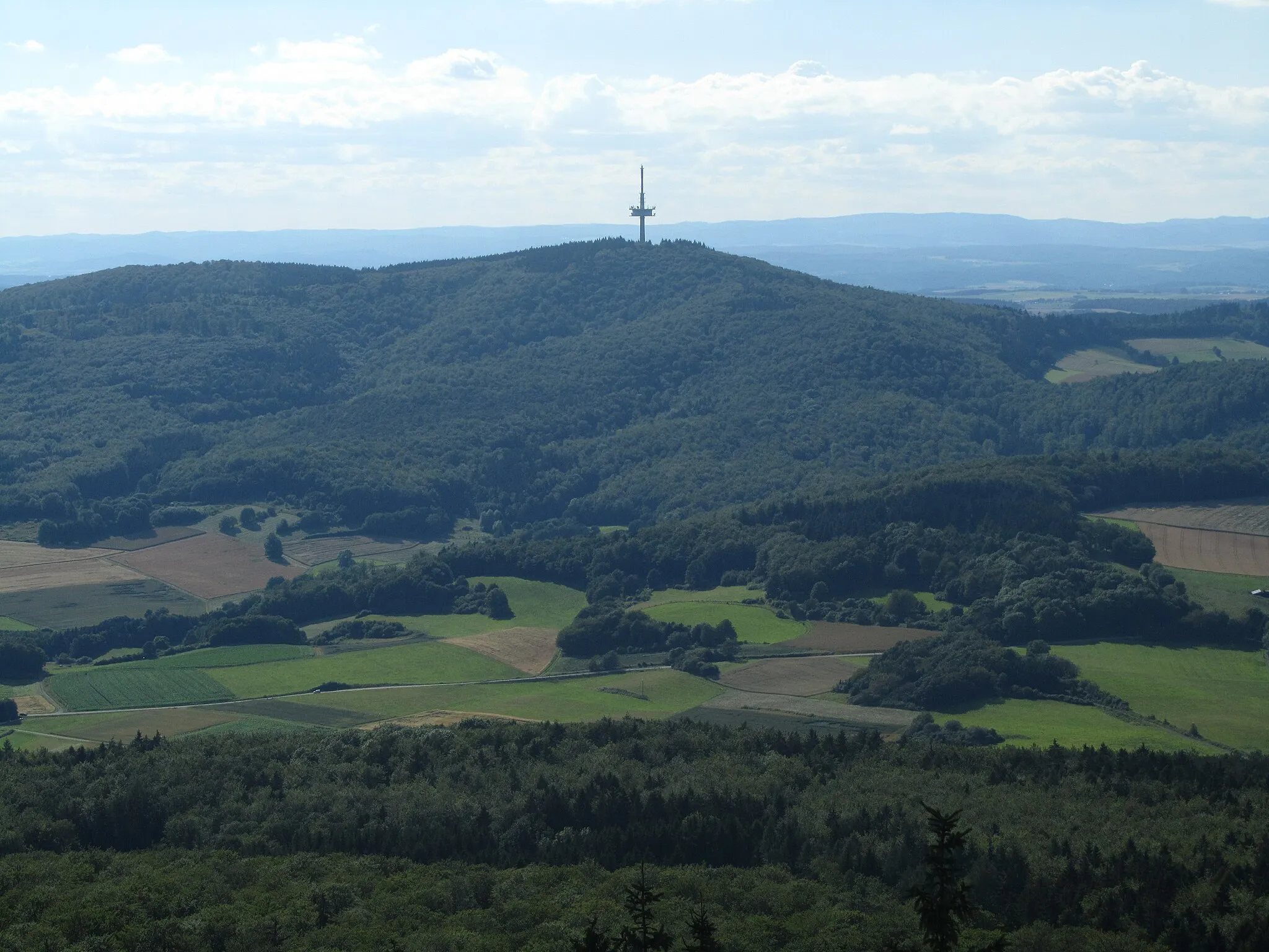 Photo showing: Das Hohe Lohr (657 m) im Kellerwald (Hessen), fotografiert vom Aussichtsturm auf dem Wüstegarten (675 m). Im Hintergrund Teile des Rothaargebirges.