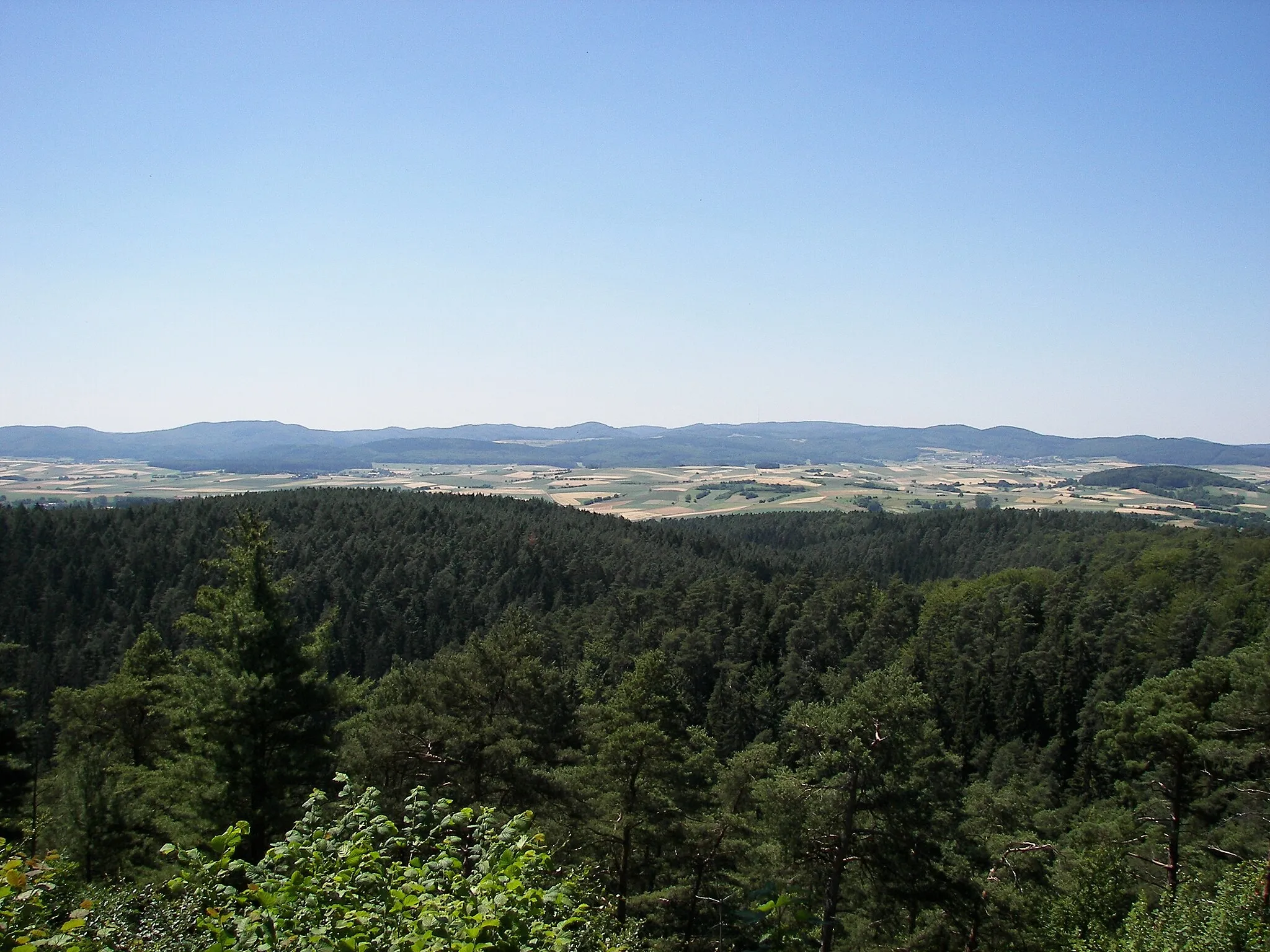 Photo showing: de:Burgwald, Blick ins Wetschaftstal, vom Christenberg aus gesehen; im Hintergrund die Sackpfeifen-Vorhöhen im Rothaargebirge mit Kohlenberg (583 m, halbrechts, zweigipfelig), Sackpfeife (674 m, rechts der Mitte, sehr breit, mit Sendemast), Hainpracht (631 m, links davon im Hintergrund), Hassenroth (622 m, Mitte, kuppig)  und Arennest (592 m, halblinks)