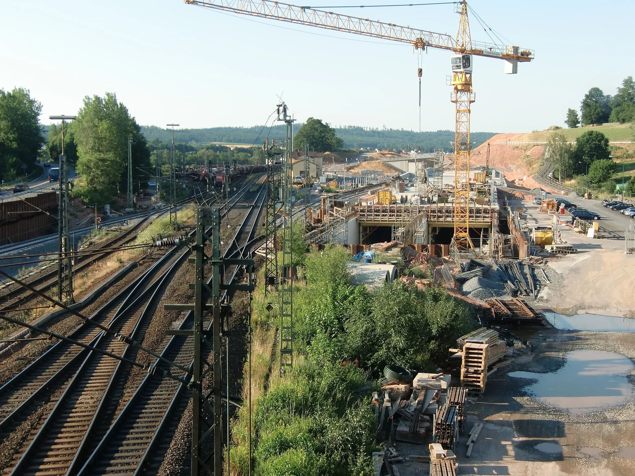 Photo showing: Construction site at train station w:Neuhof, Hesse. On the very left is Bundesstraße 40 which will be substituted by w:Bundesautobahn 66 (tunnel under construction on the right).
When completed the new railway track will be situated between the original track and the Autobahn tunnel, right of the station building.