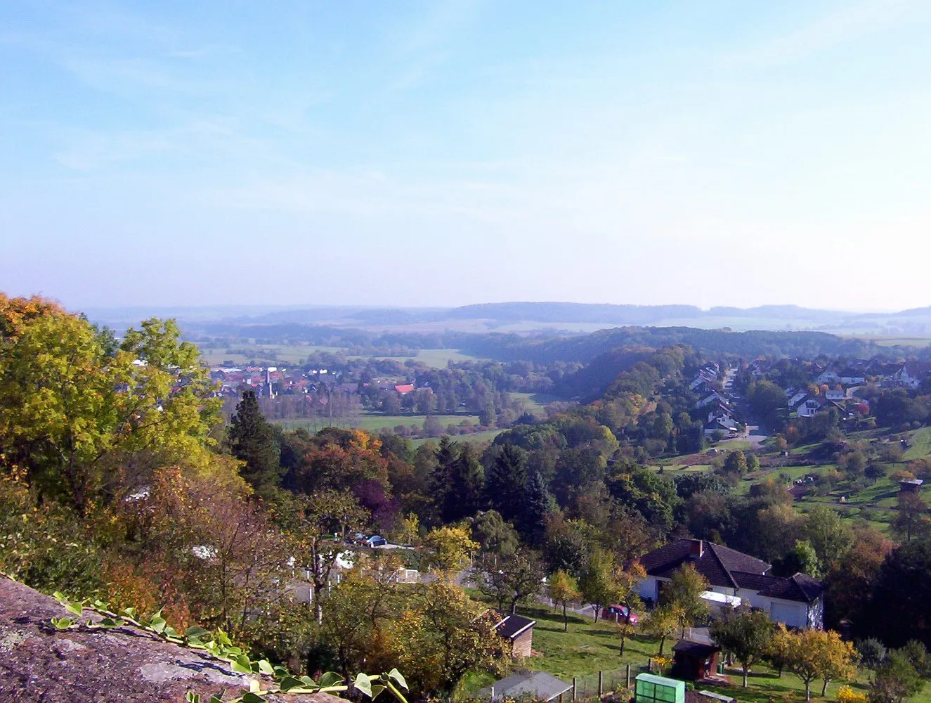 Photo showing: View from the old town of Battenberg upon the Eder river (NW Hesse, Germany) towards ESE, the Eder valley with the village of Battenfeld (part of municipality of Allendorf upon the Eder river) being in the midground and background of the left half of the picture. The midground of the right half shows the neigbourhood along Erfurter Straße and Eisenacher Straße above the Eder river valley at the eastern outskirts of Battenberg.