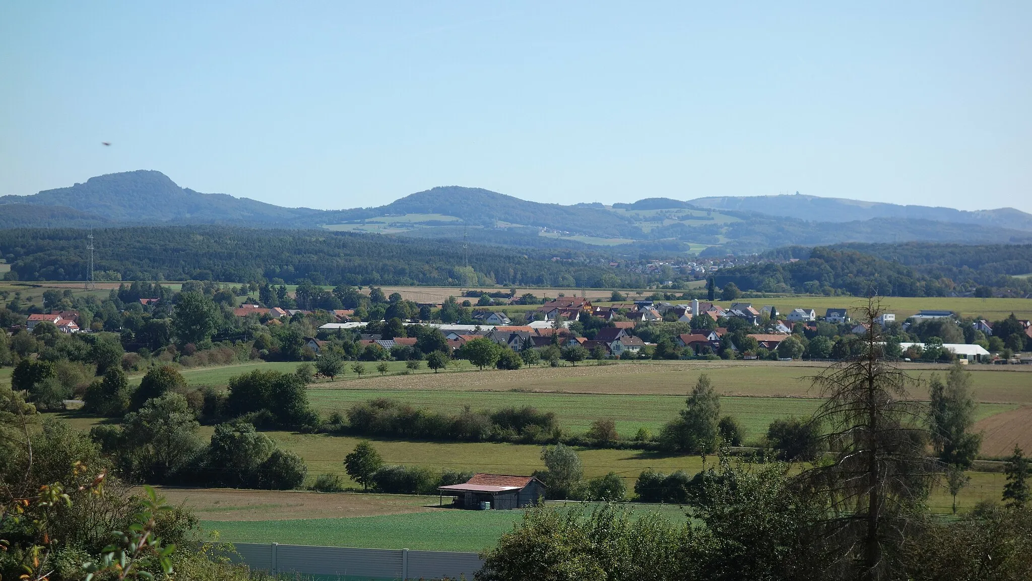 Photo showing: Almendorf (Haunedorf, Gemeinde Petersberg, Landkreis Fulda) - von Nordwesten gesehen. Im Hintergrund die Rhön mit Milseburg, Stellberg, Weiherberg, Wasserkuppe und Pferdskopf.